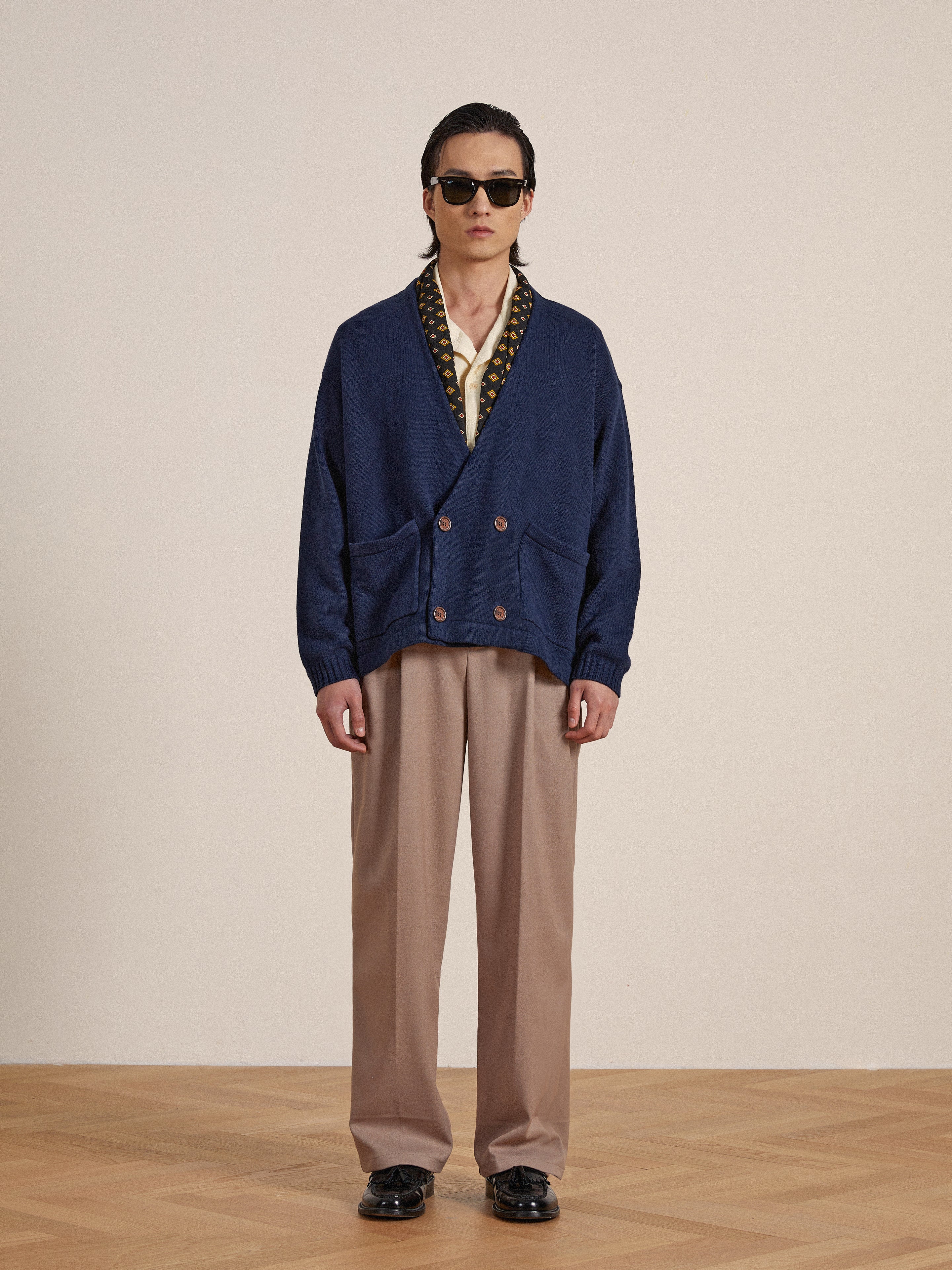 A man wearing a blue Larsi Double Breasted Knit Cardigan and tan pants by Found.