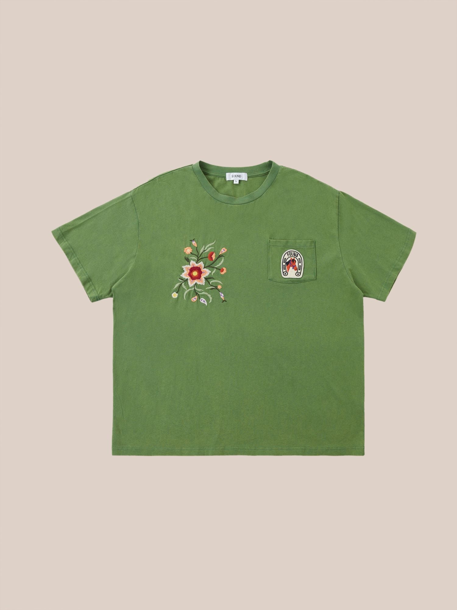 Pine Needle Farm Tee by Found, with intricate embroidery on the left side and a patch on the right chest, displayed on a beige background.