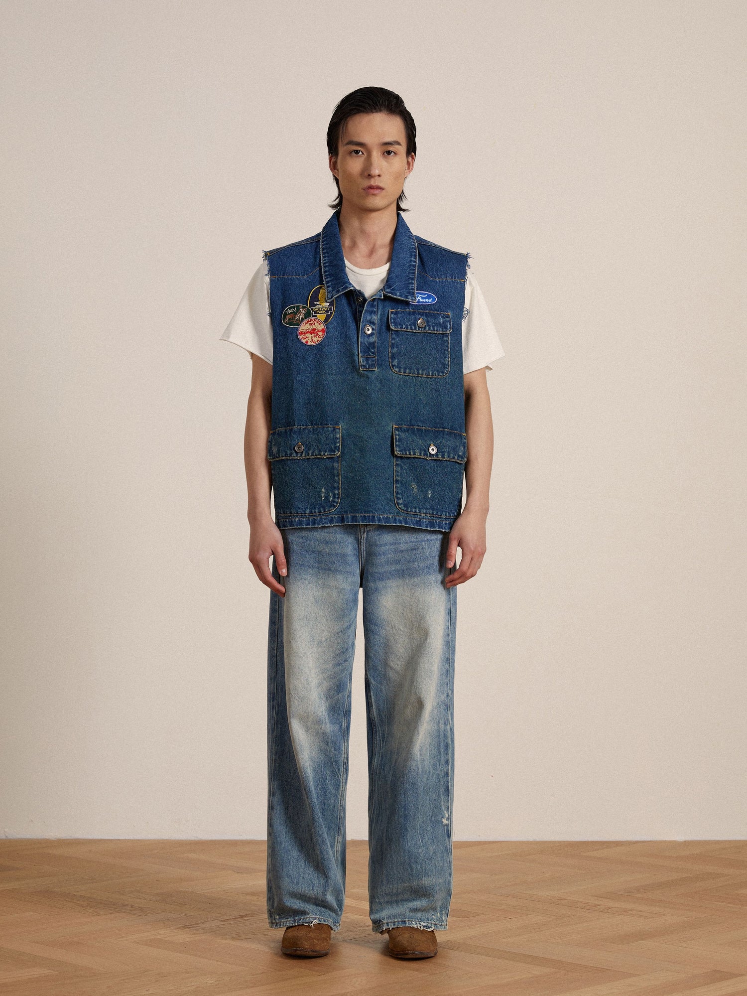 A man wearing a Found Raw Cut Patch Mechanic Denim Vest and jeans.