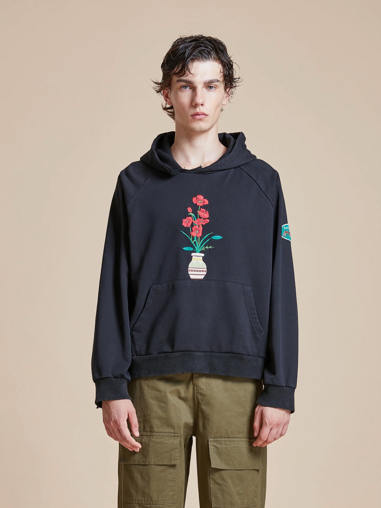 A man wearing a Found Flowers Vase Hoodie, with vintage feel and delicate flowers on it.