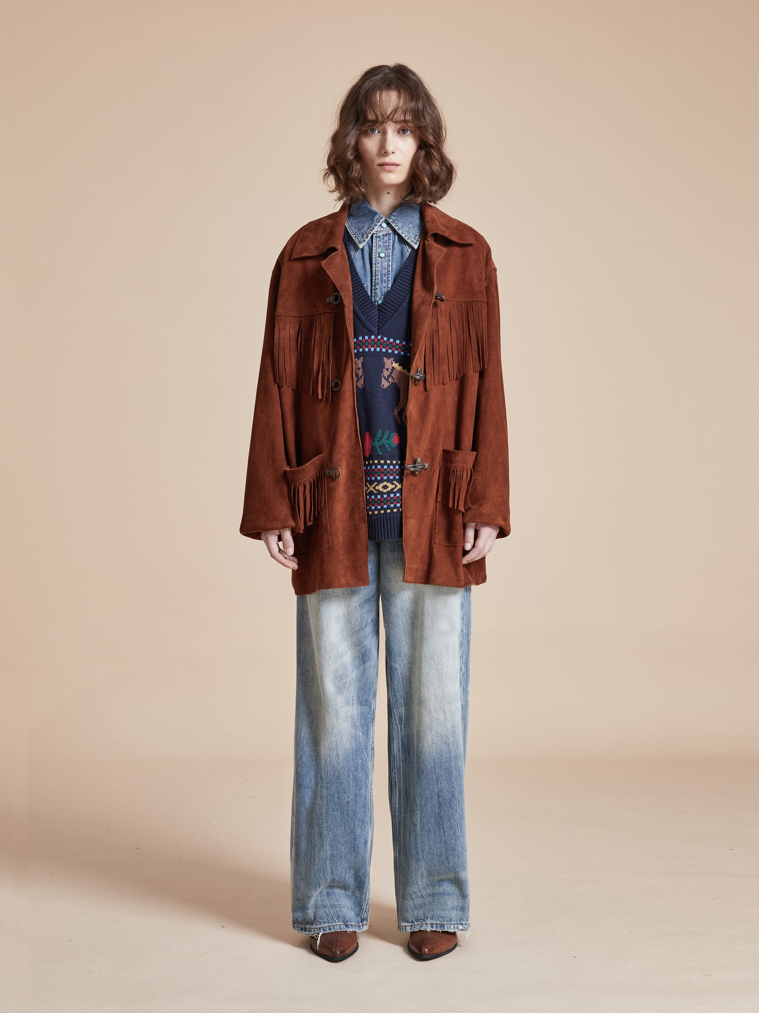 A model wearing the Found Tobacco Fringe Suede Buckle Jacket and jeans.