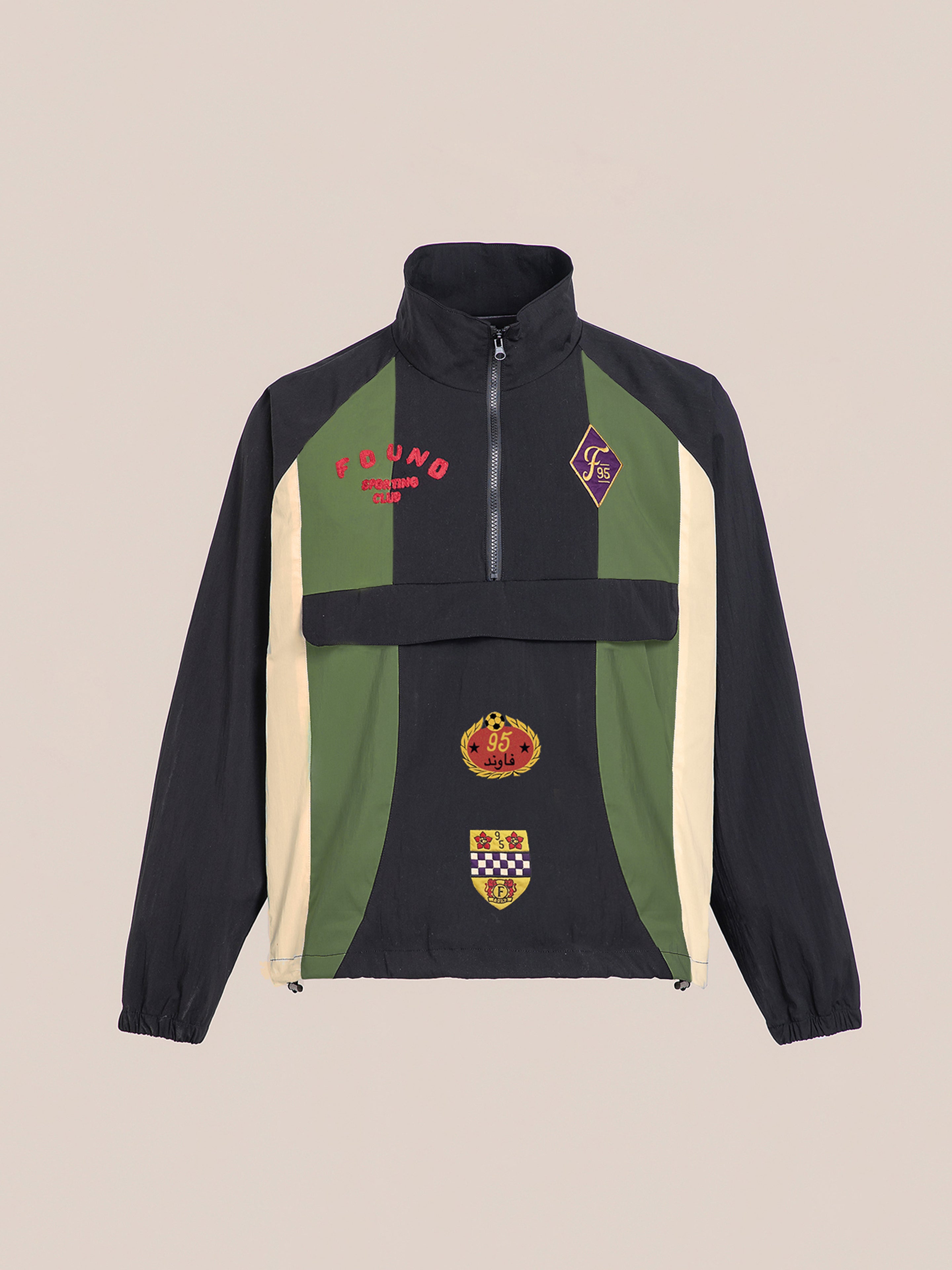 The Sporting Club Pullover Jacket by FOUND is a green and black lightweight nylon piece with patches, a high collar, half-zip front, and elastic cuffs—a perfect nod to vintage style.