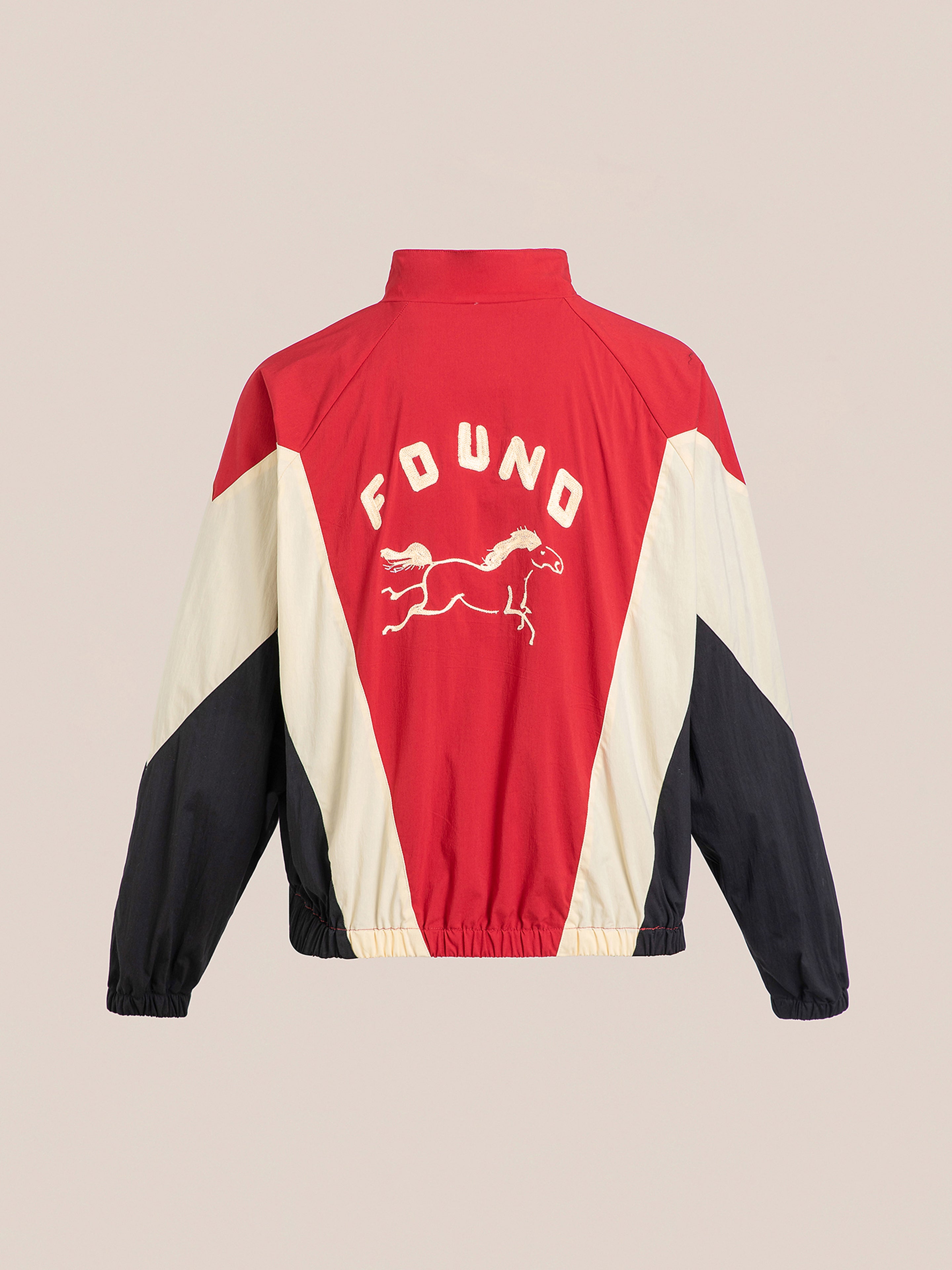 The Pine and Rose Track Jacket by FOUND is a red, white, and black unisex design with a galloping horse graphic on the back. It features long sleeves and elastic cuffs, making it perfect sportswear for those who value style and function.