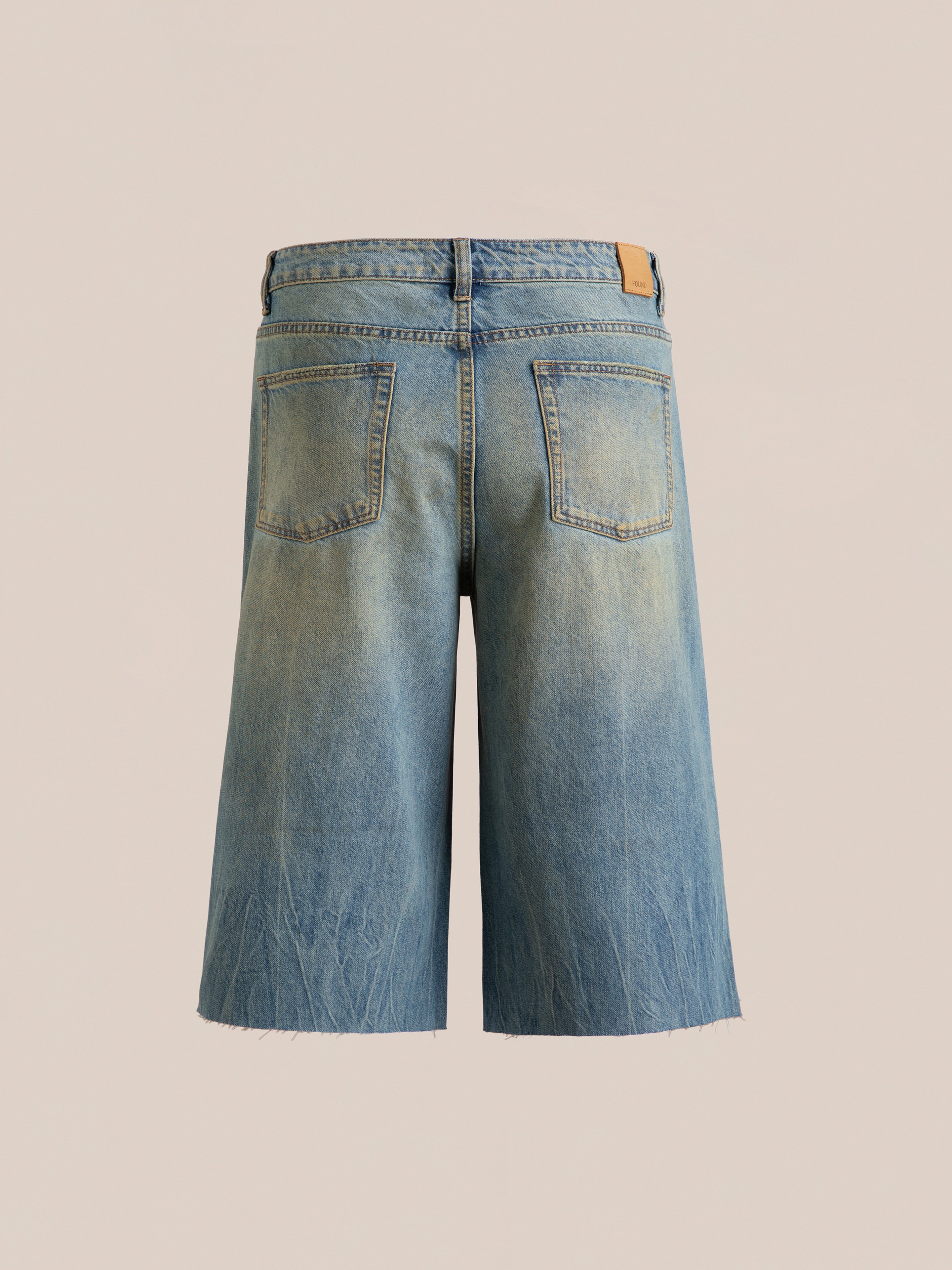 Back view of FOUND's Lacy Jean Jorts, featuring mid-length faded denim with frayed hems and two back pockets, set against a neutral background.