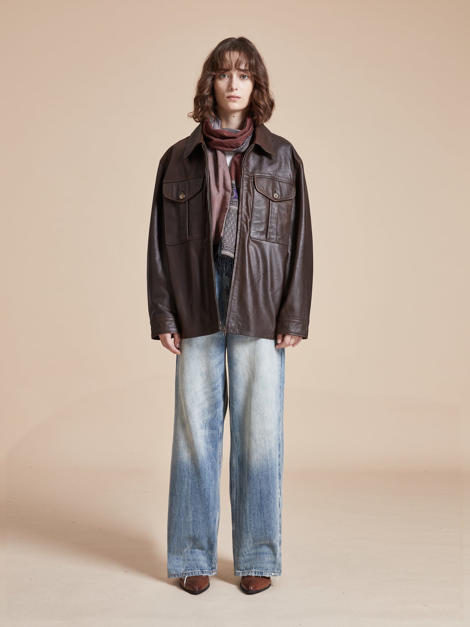 A model wearing a Found Sepia Leather Overshirt and jeans.