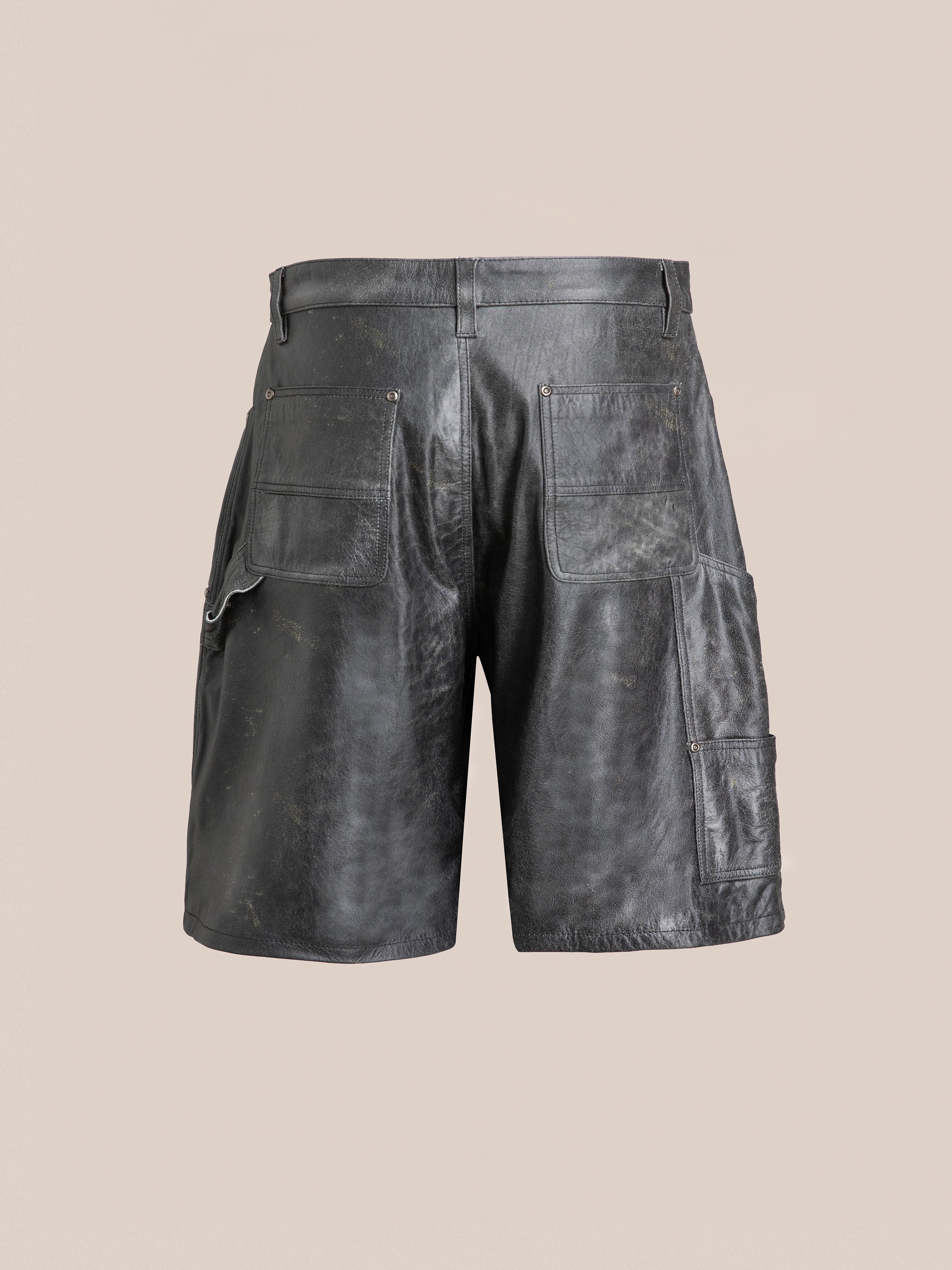 A pair of Found Distressed Genuine Leather Carpenter Shorts in black, featuring multiple pockets and a slightly worn appearance, viewed from the back against a plain backdrop.