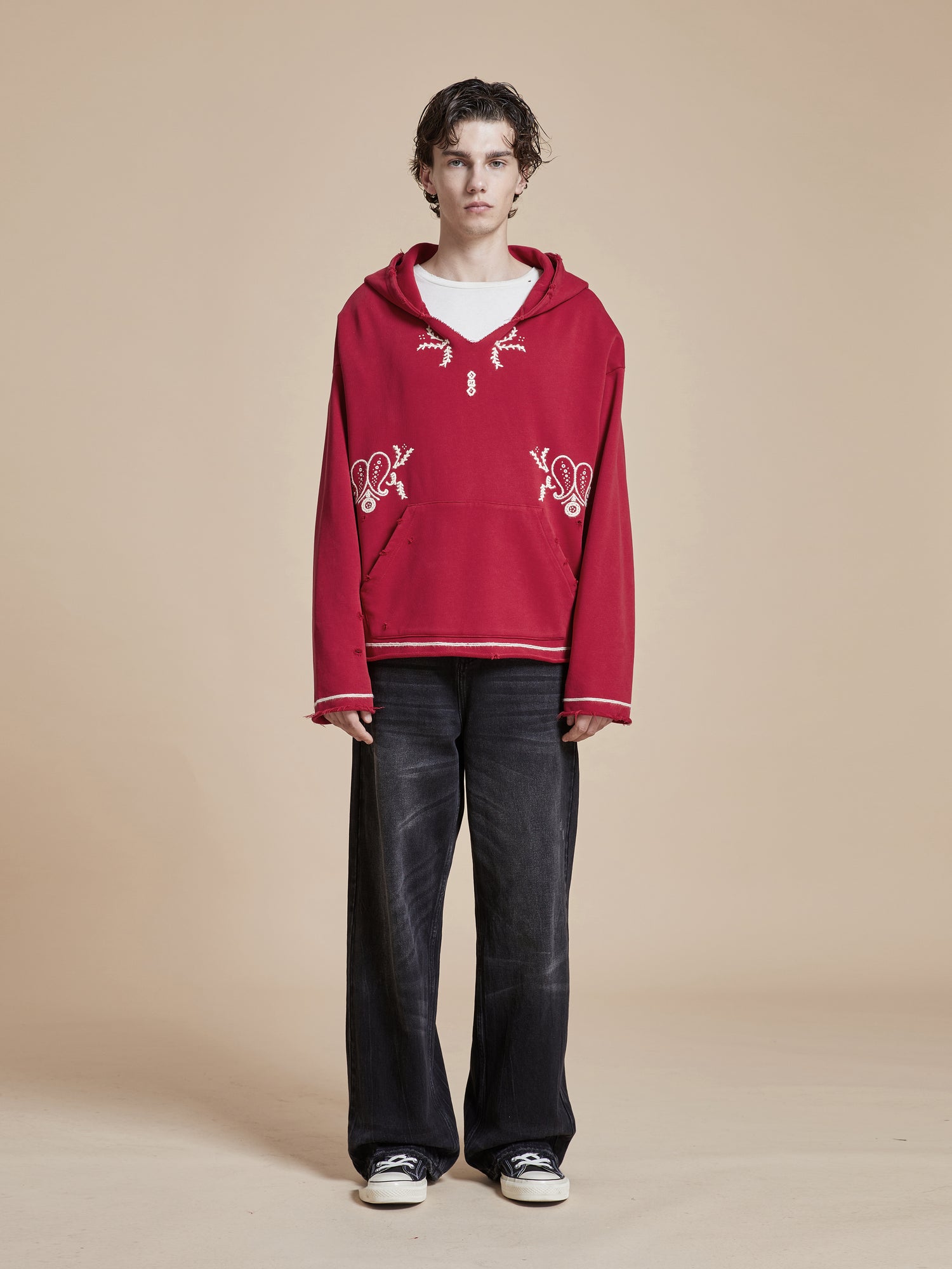 A man wearing a Found Phulkari Embroidered Hoodie and black pants.