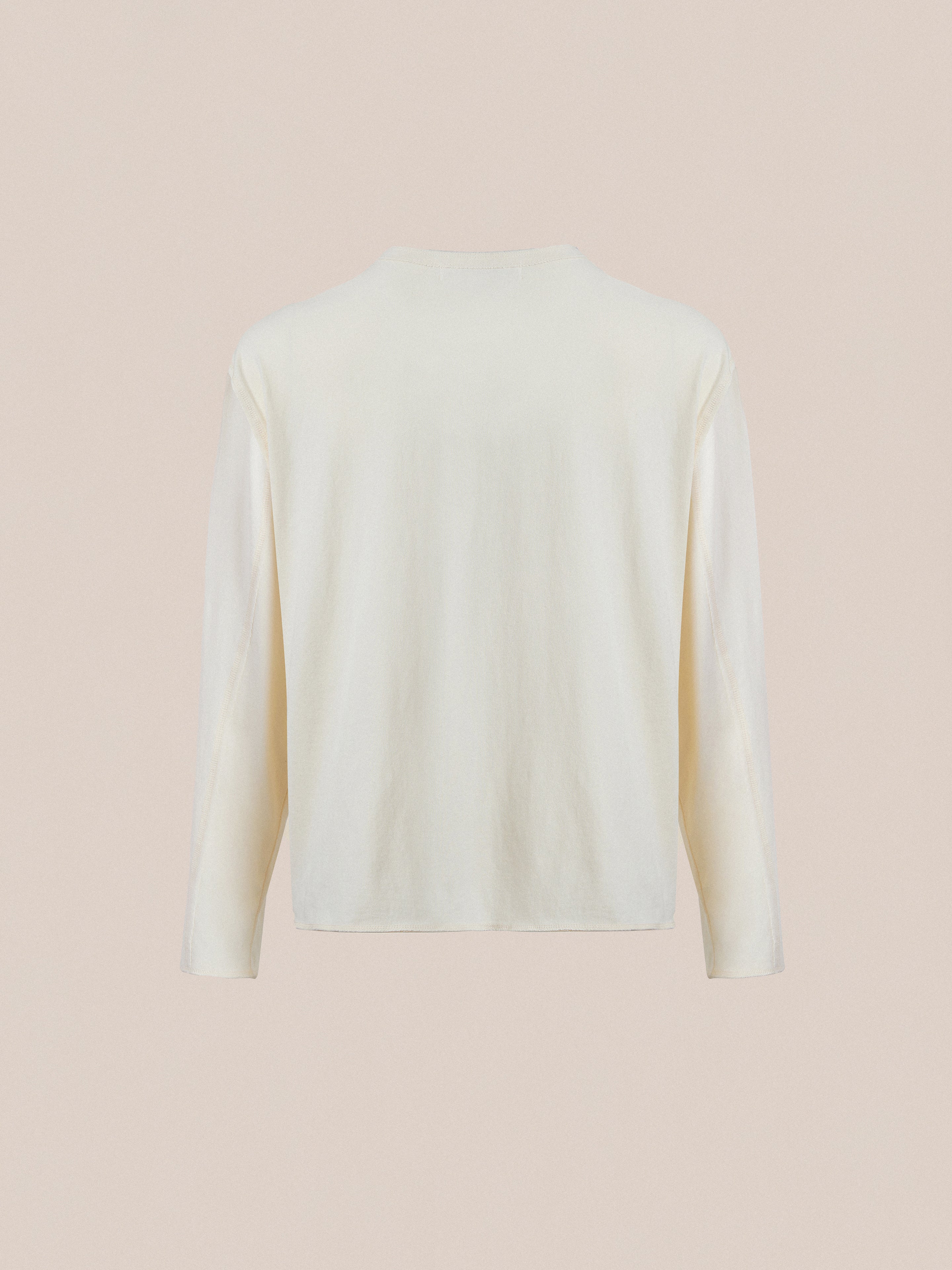 The FOUND Reversed LS Tee is a cream-colored, unisex long sleeve shirt with a distressed neckline, shown from the back against a plain beige background. Effortless style for any occasion.