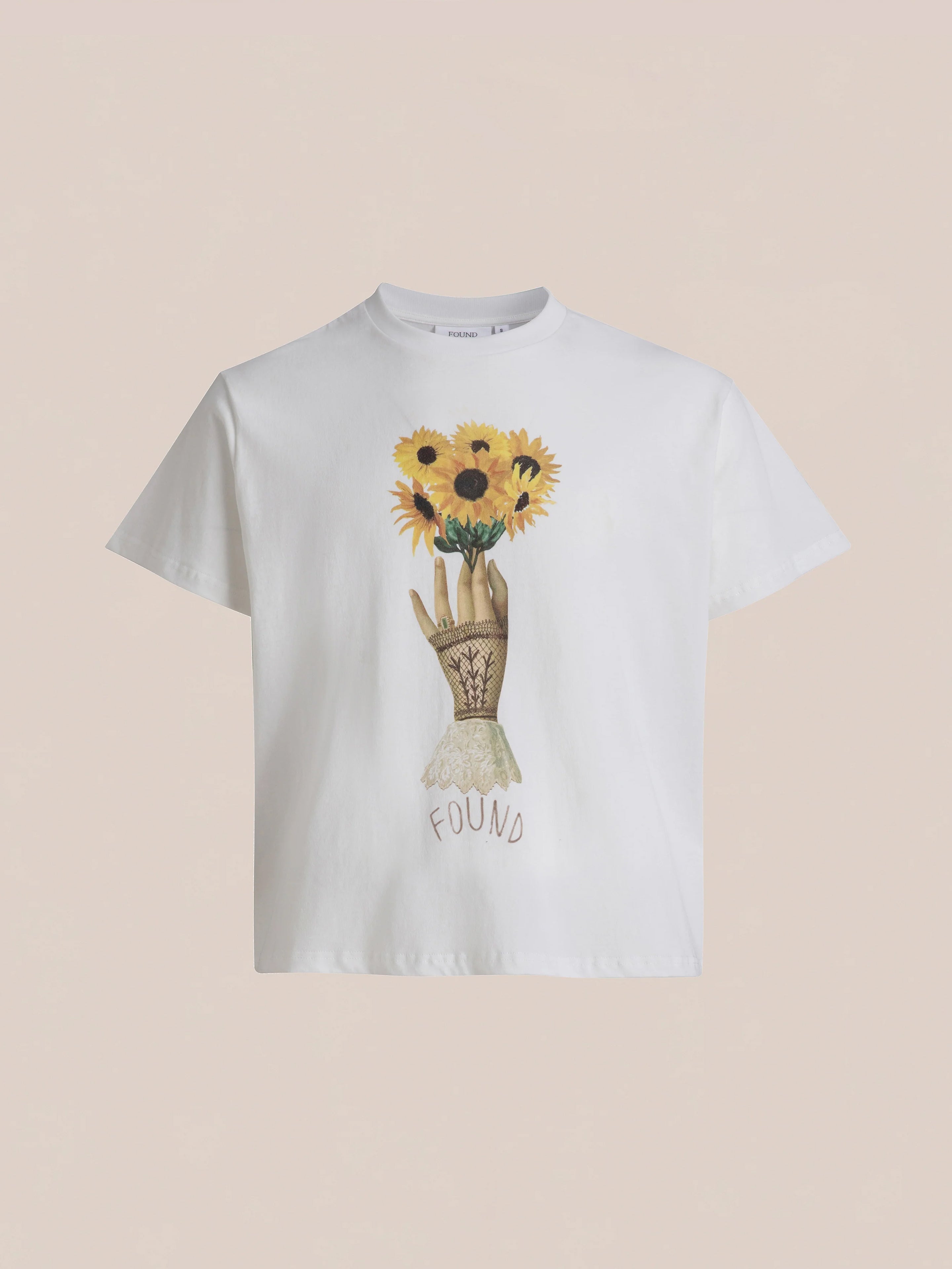 White Sunflower Tee from FOUND brand, featuring a vintage-feel floral graphic of a hand holding sunflowers with the word "FOUND" written below.