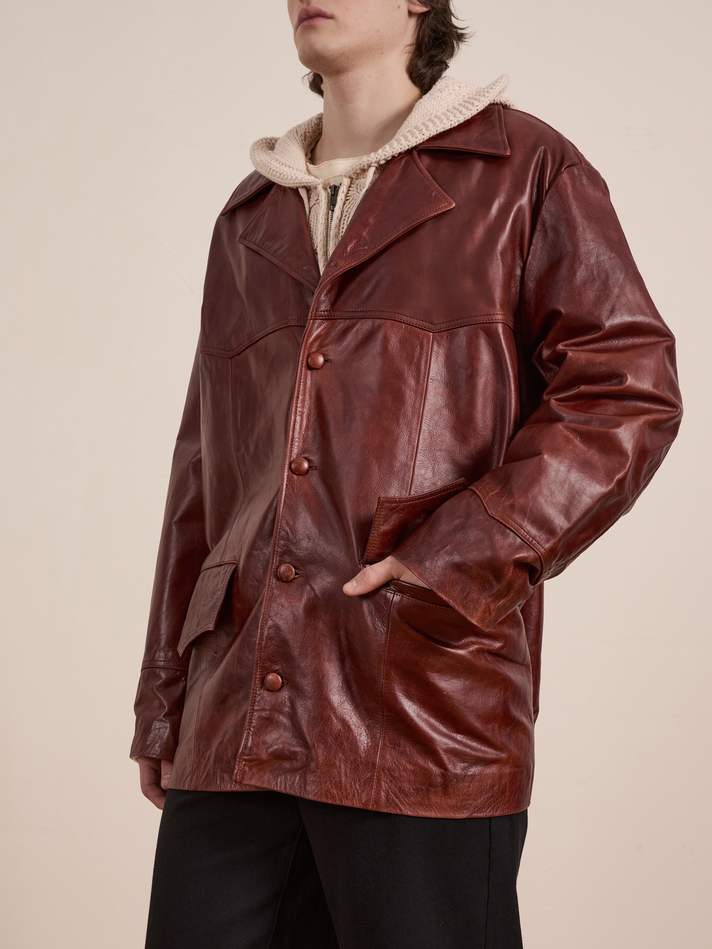 Wearing the FOUND Claret Western Oversized Leather Blazer over a beige hoodie, one hand rests comfortably in the pocket.
