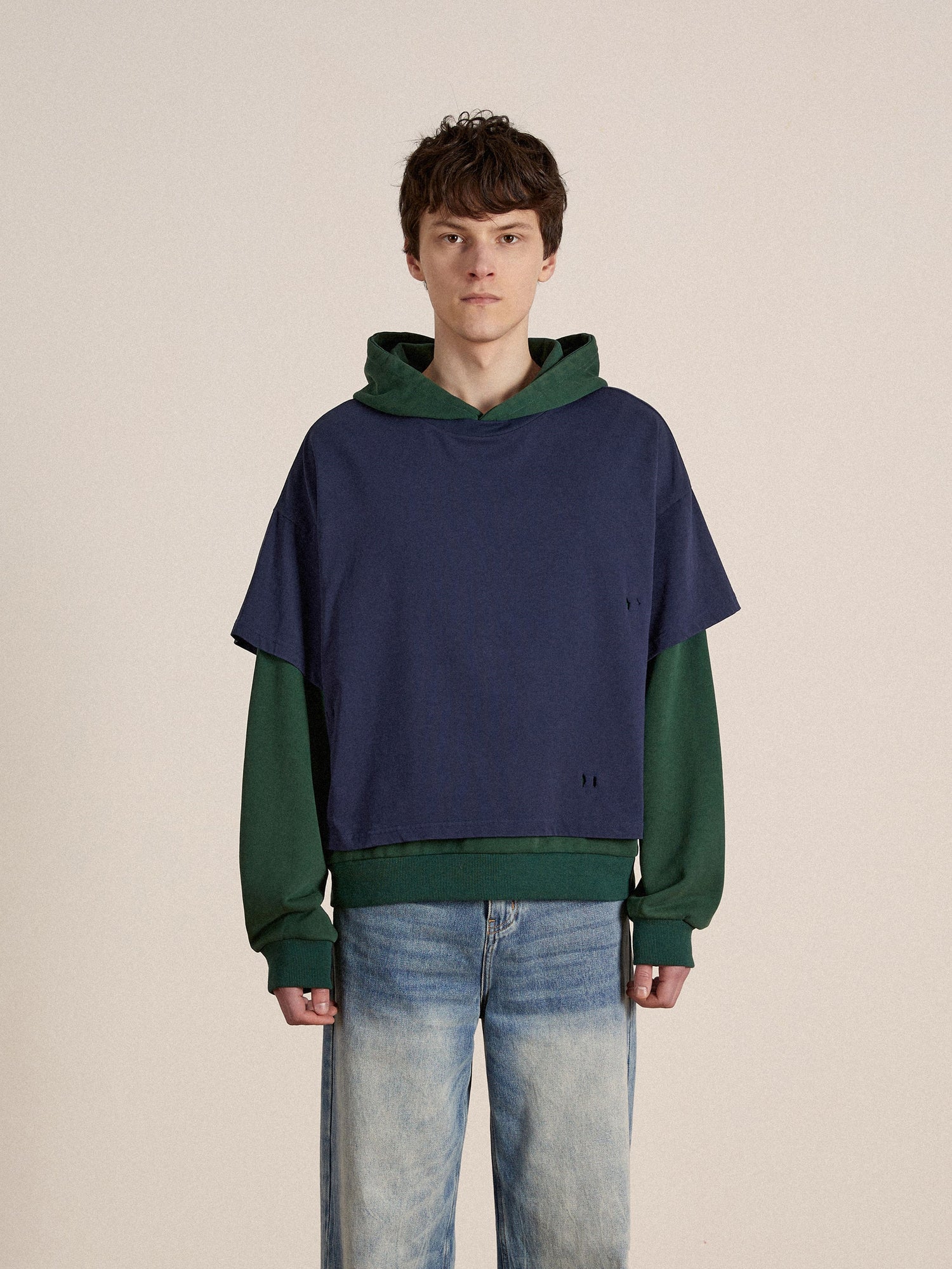 A man wearing a blue and green Found double layer hoodie and jeans.