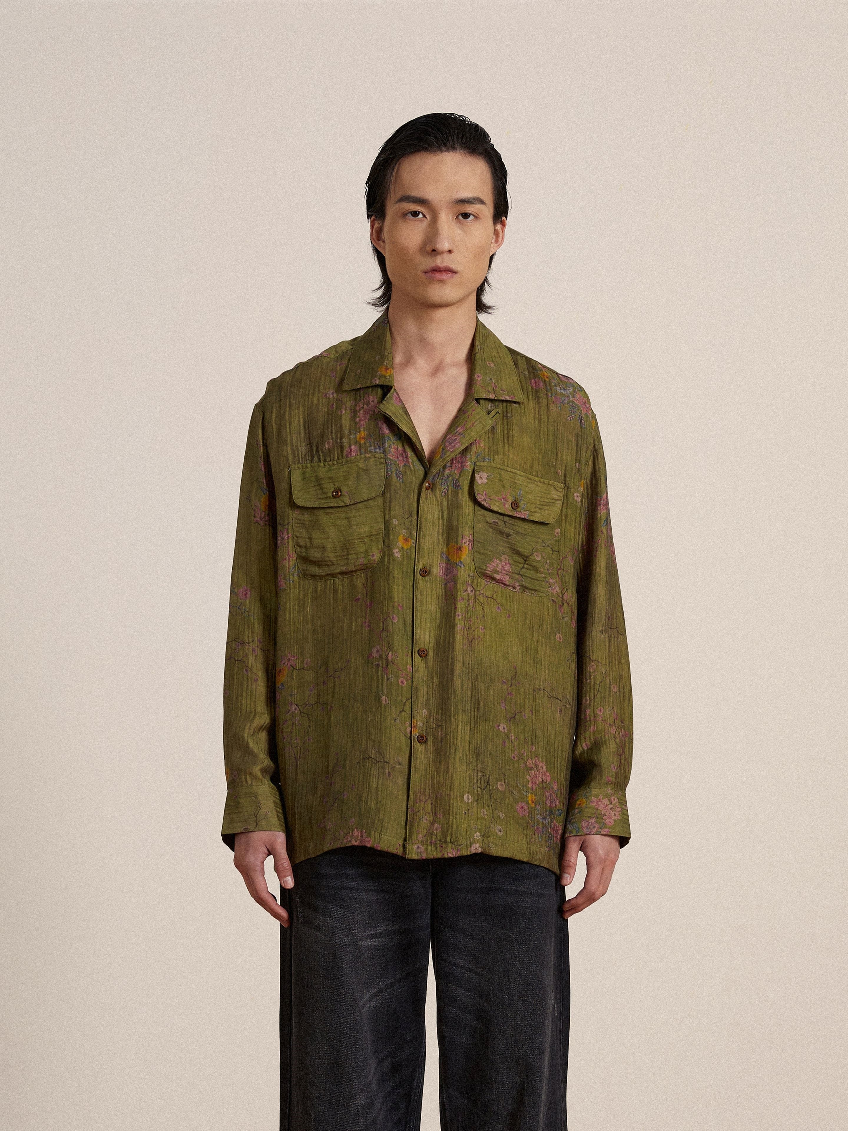 A man wearing a Found Floral Moss Long Sleeve Camp Shirt and black pants.