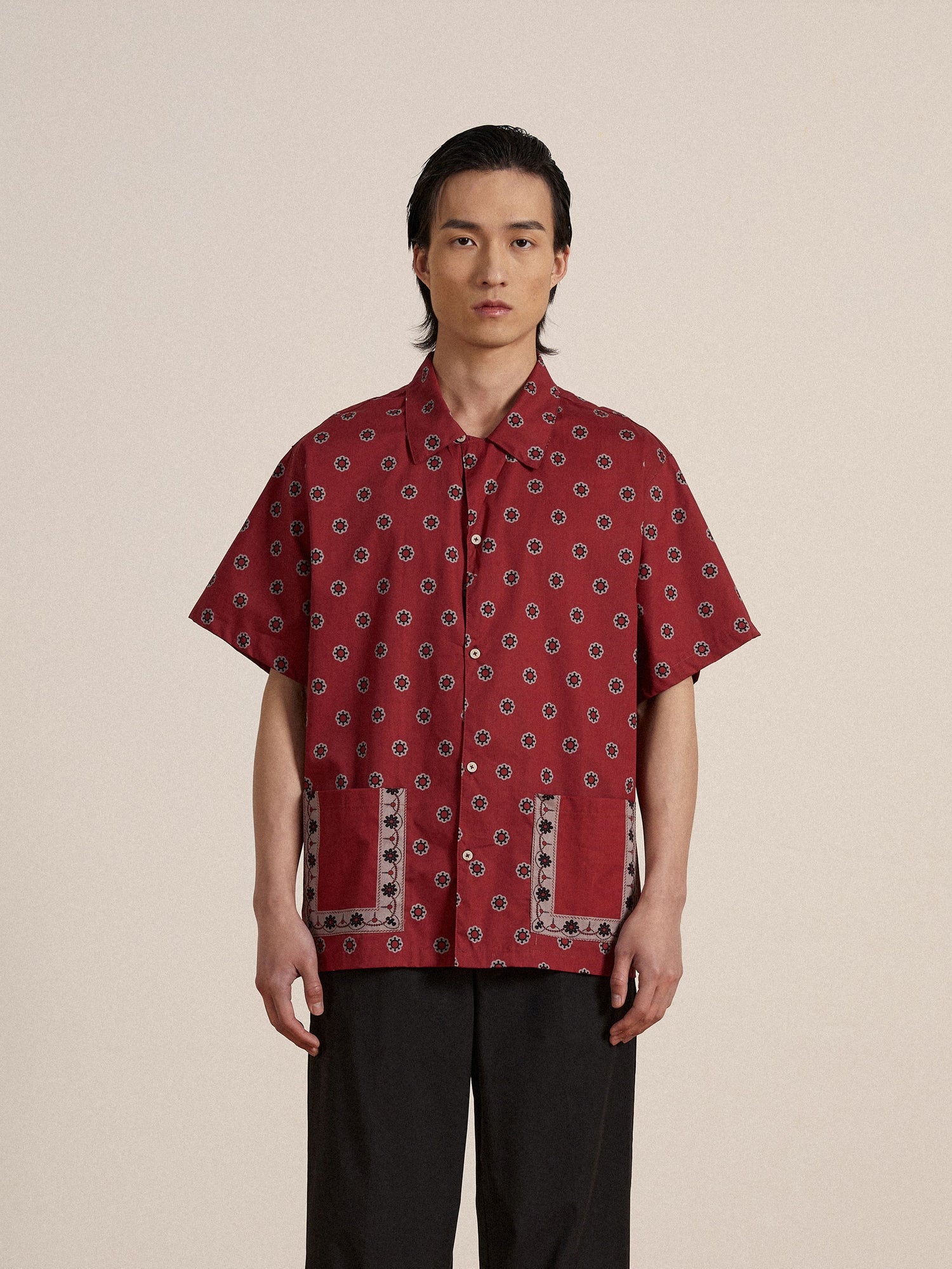 A man wearing a Found Red Motif SS Camp Shirt and black pants.