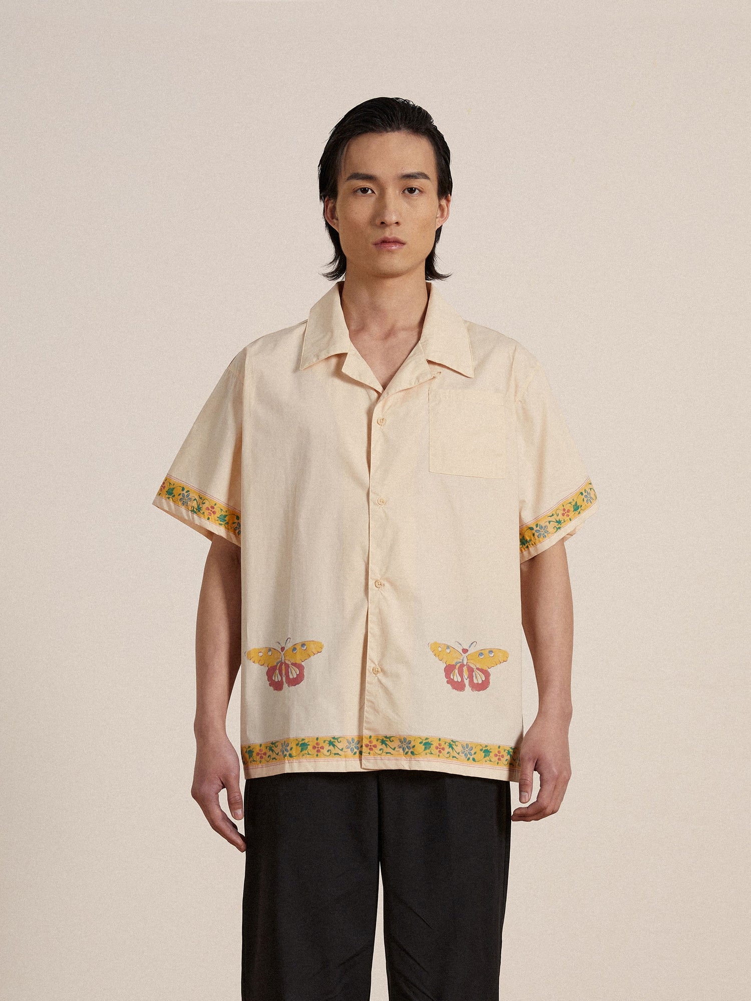 A man wearing a Found Moth Camp Shirt and black nylon pleated pants.