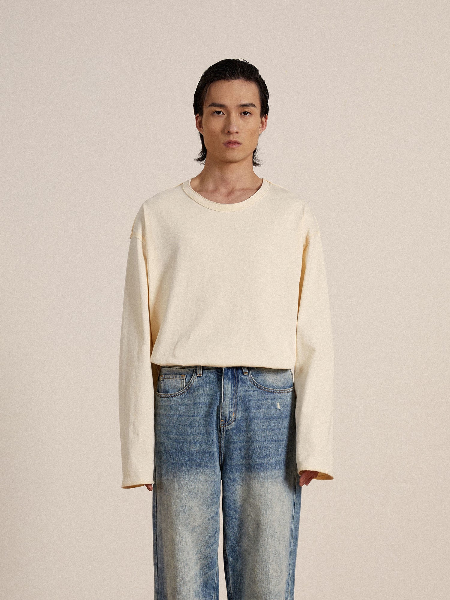 The model is wearing a cream Reversed LS Tee by Profound with reversed seams and blue jeans.