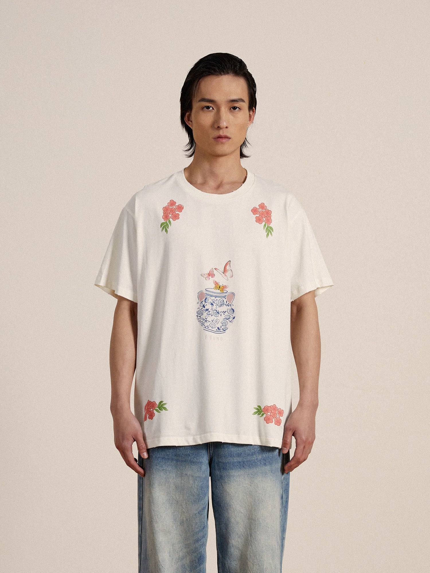 A man wearing a Found Flower Pot Tee with flowers on it, exuding springtime charm.
