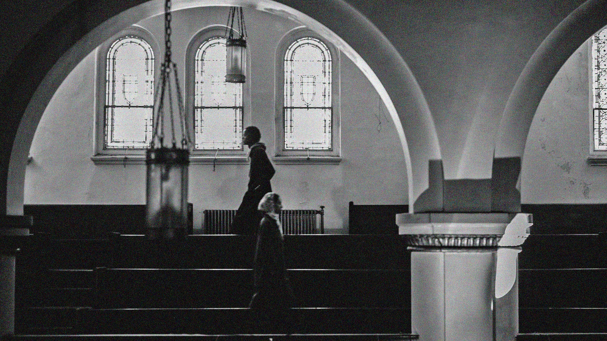 A black and white photo of a woman standing in a church.