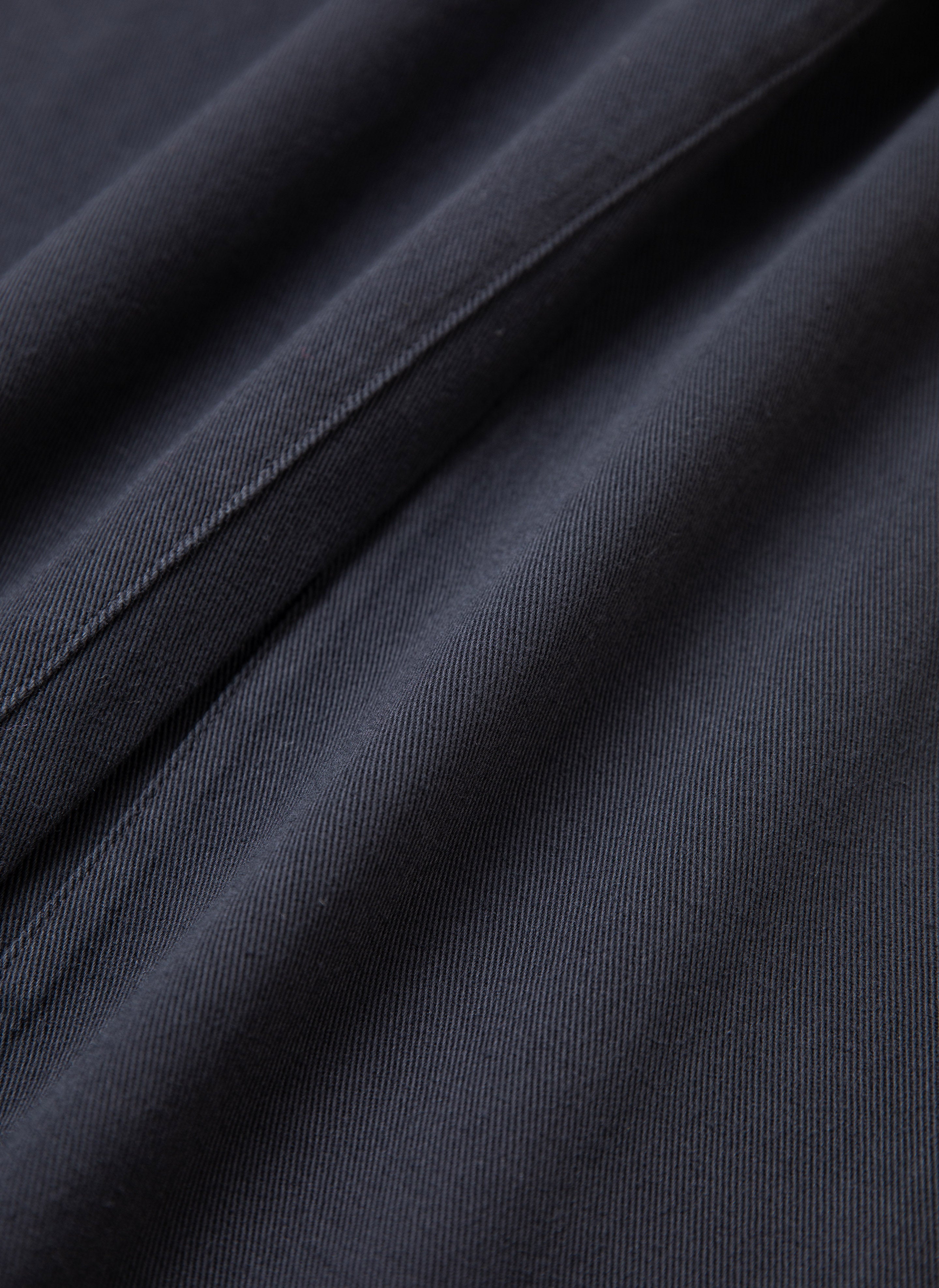 Close-up of dark fabric with fine diagonal lines, showing detailed texture and stitching, akin to the meticulous craftsmanship found in a pair of FOUND's Lacy Baggy Jeans.