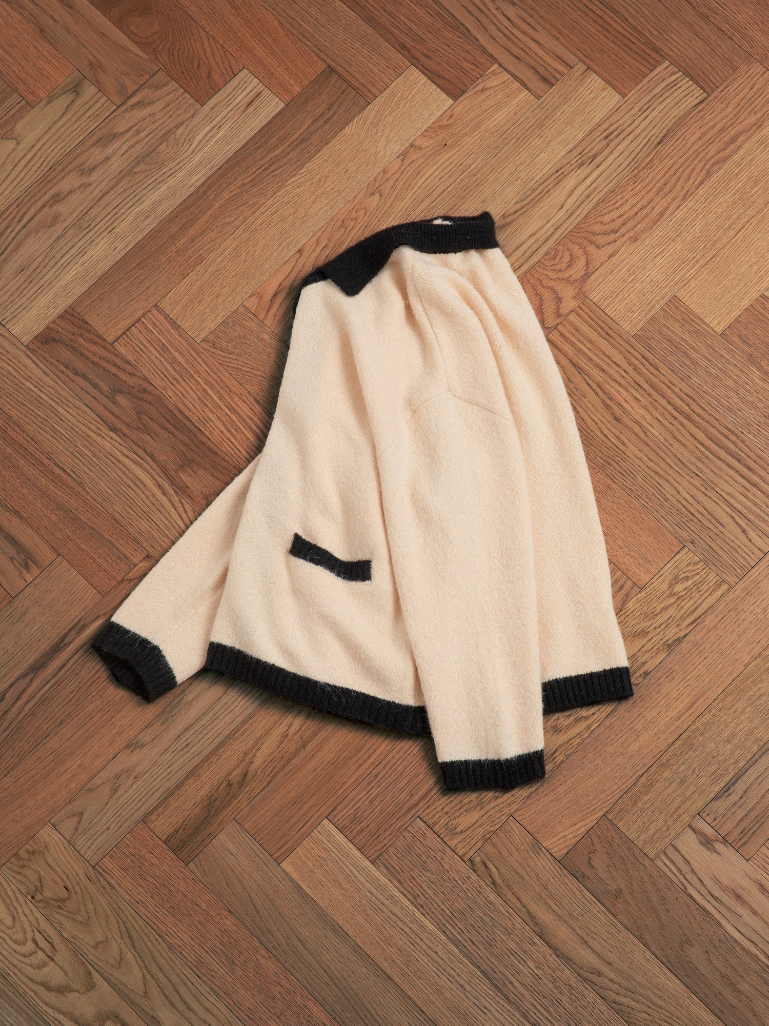 A luxurious Sima Contrast Collar Knitted Cardigan sweater with wooden buttons on a wooden floor.