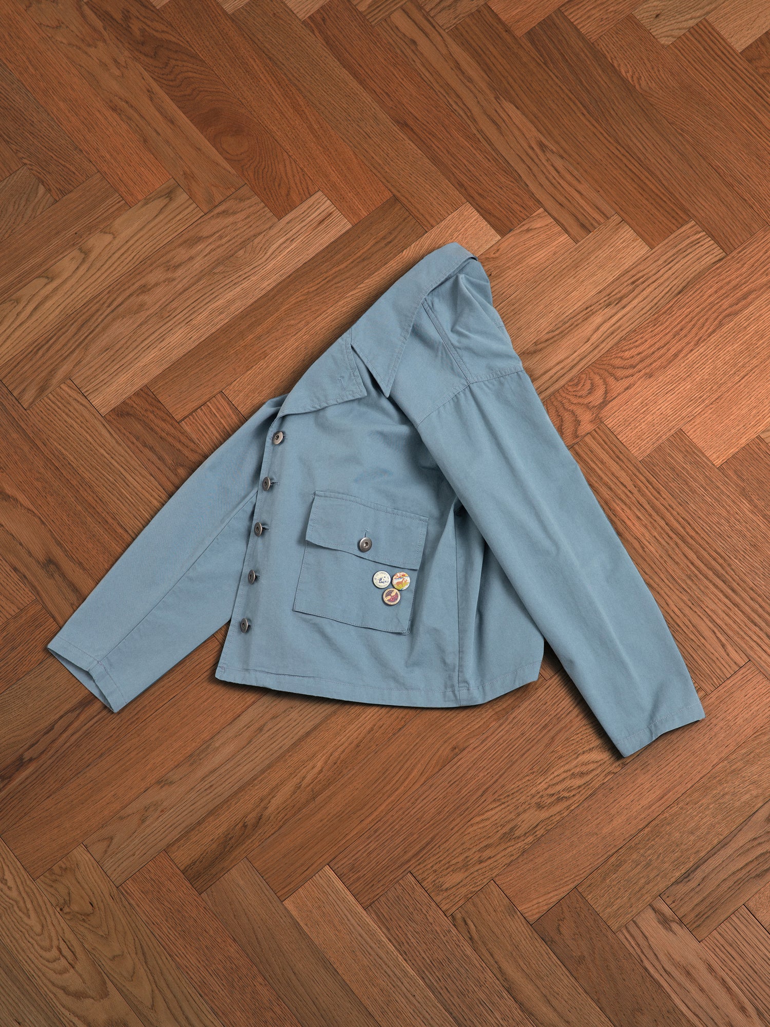 A vintage Found Patina Work Jacket laying on a wooden floor.