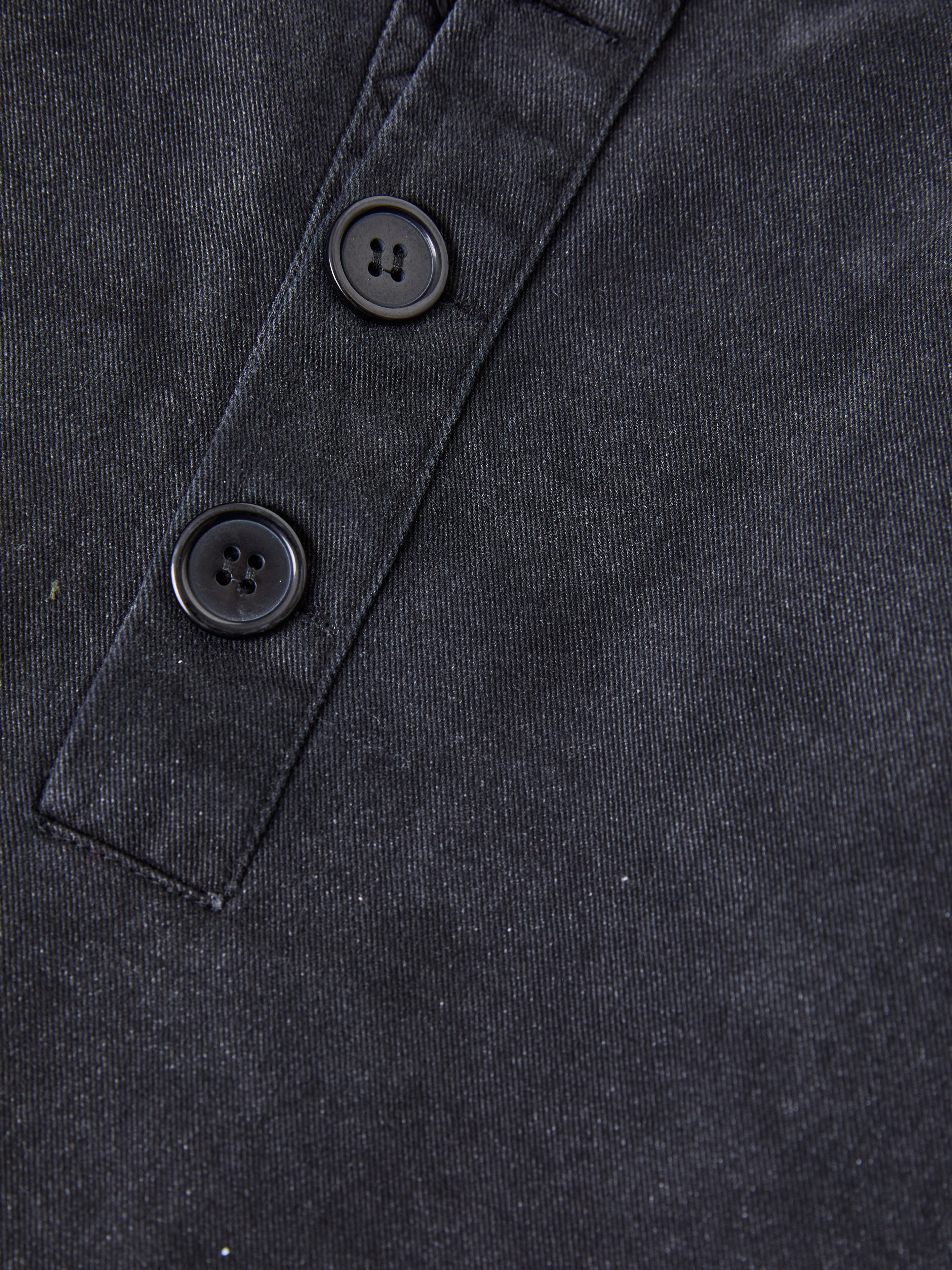 Close-up of FOUND's Washed Twill Pocket Anorak Jacket, showcasing a vintage black design with a placket featuring two sleek black buttons.