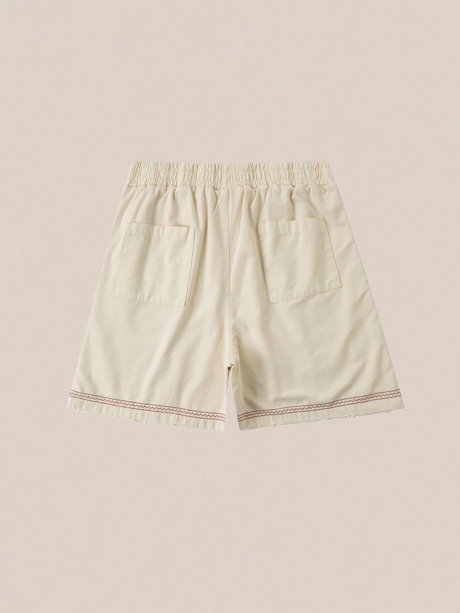 Profound's Embroidered Horse Shorts are beige cotton twill shorts with an elastic waistband and two back pockets, accented by red stitching near the hem and playful embroidered horse motifs.