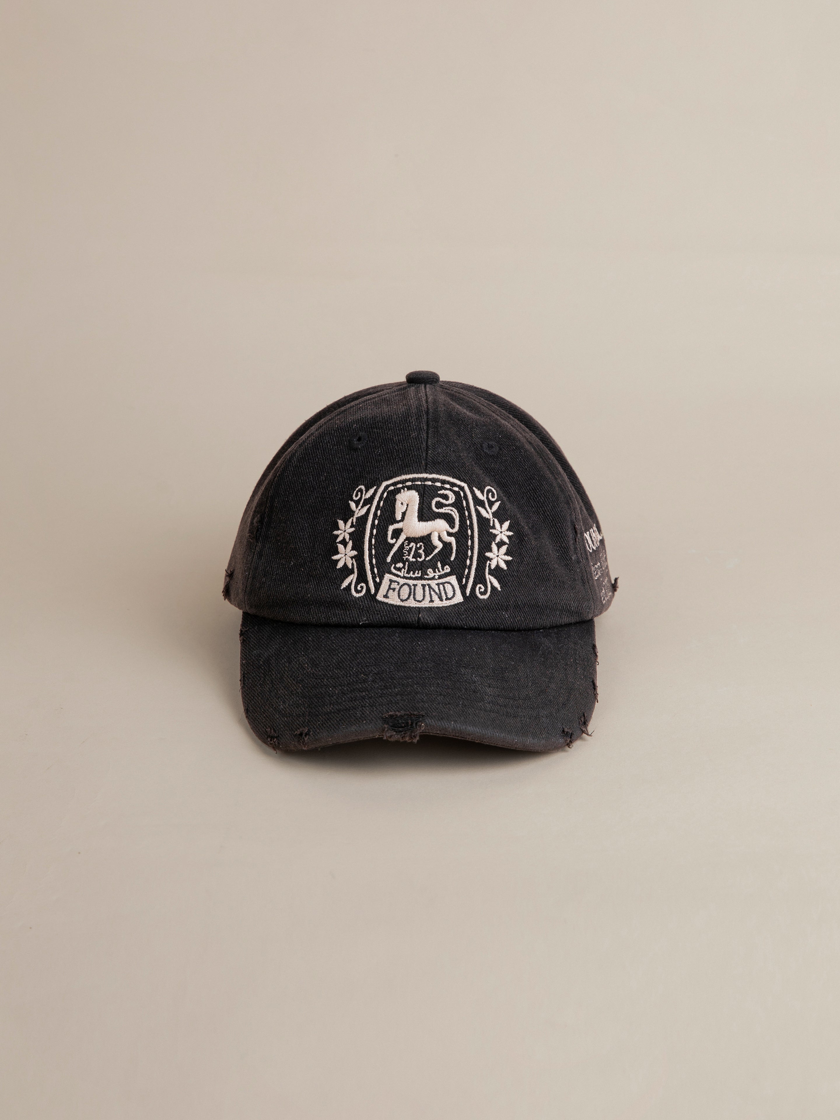 A worn black FOUND Logo Crest Cap with a vintage wash featuring a white embroidered logo that reads "23, Found." The cap has a slightly distressed look, reminiscent of the classic Logo Crest Cap style.