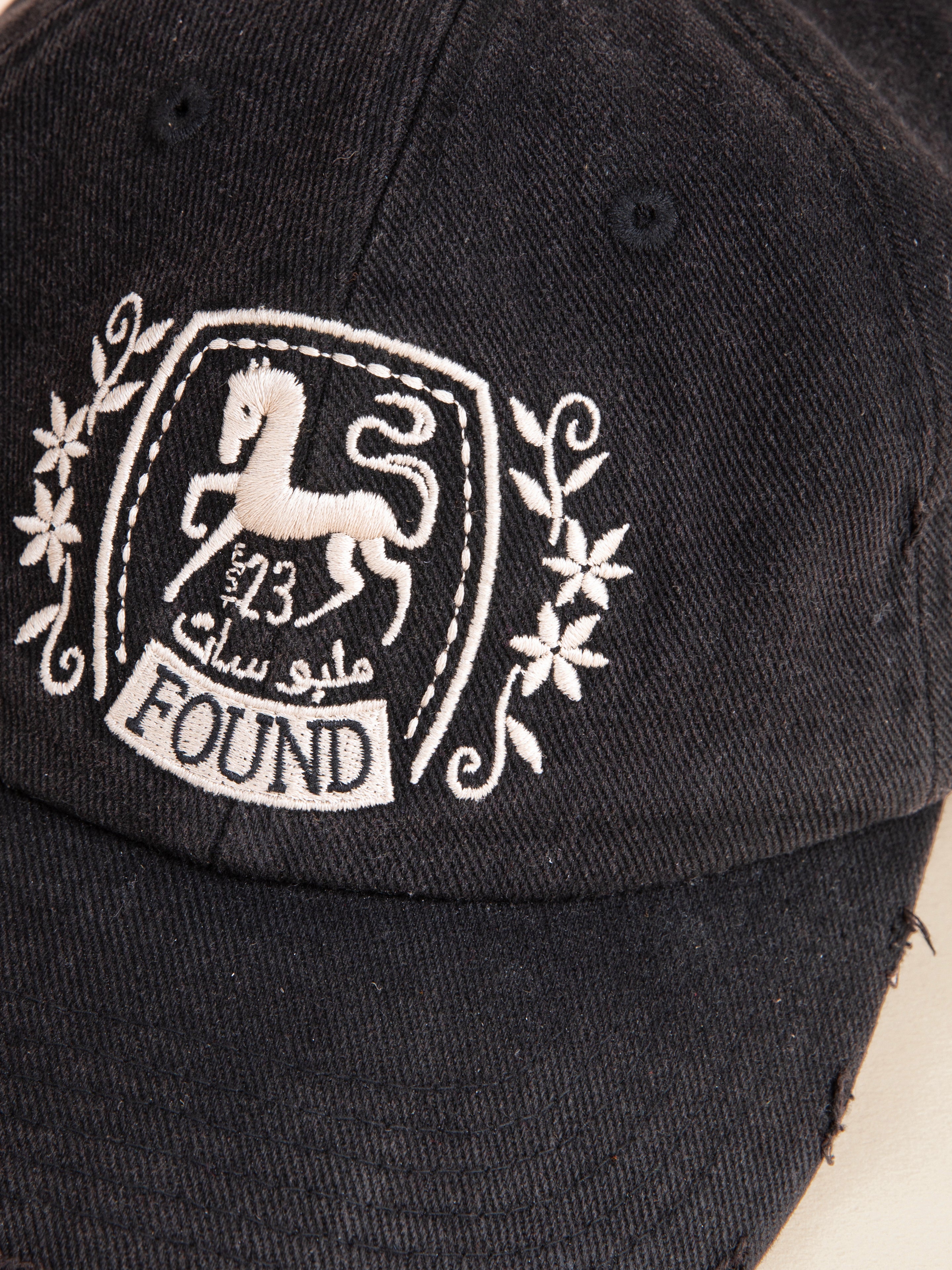 Close-up of a black Logo Crest Cap from FOUND, featuring an embroidered horse logo with the number 523 and the word "FOUND" below.