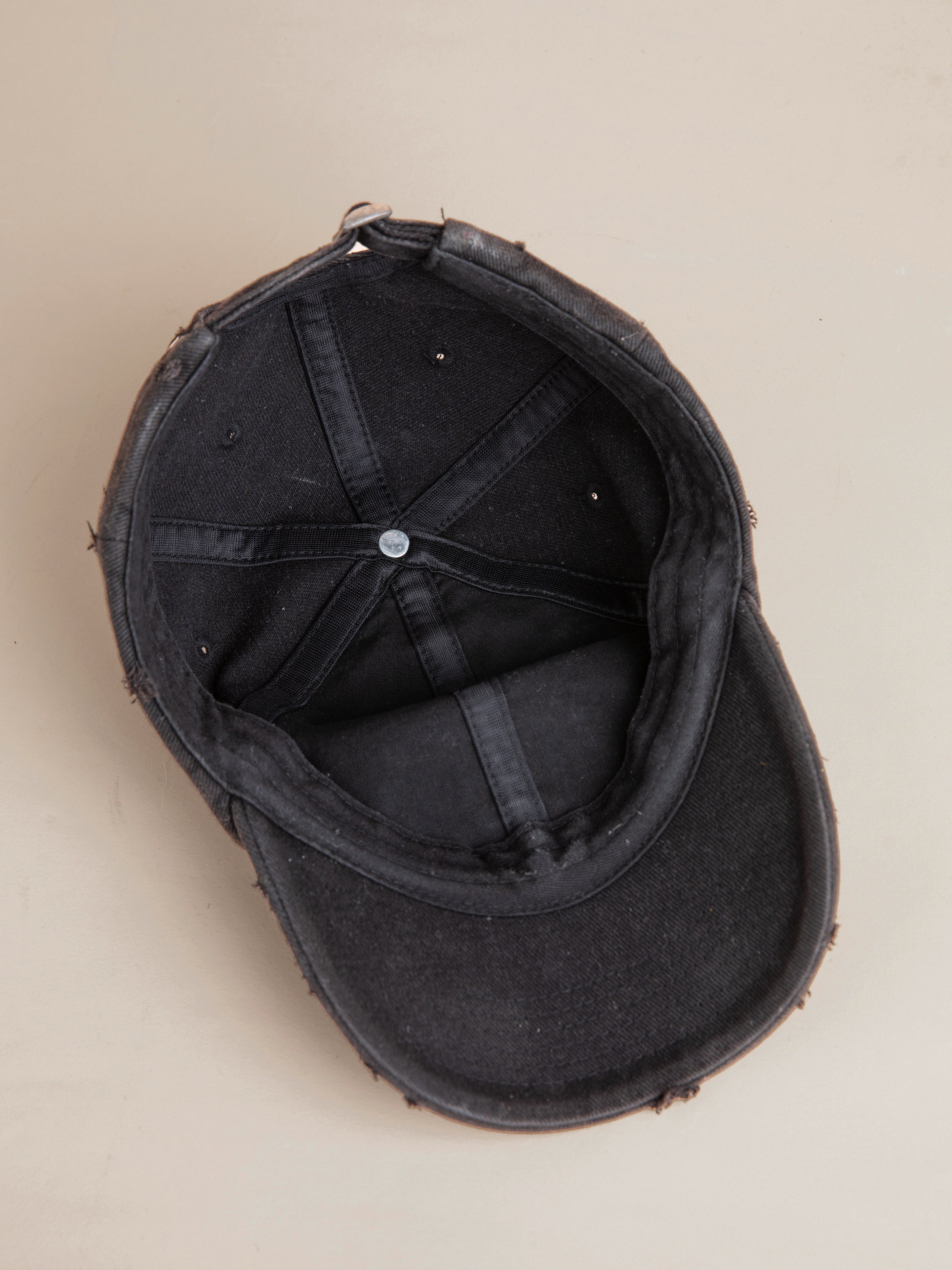 An old, worn FOUND Logo Crest Cap viewed from the inside, showing visible signs of fraying and use, features a vintage wash and an embroidered horse logo.