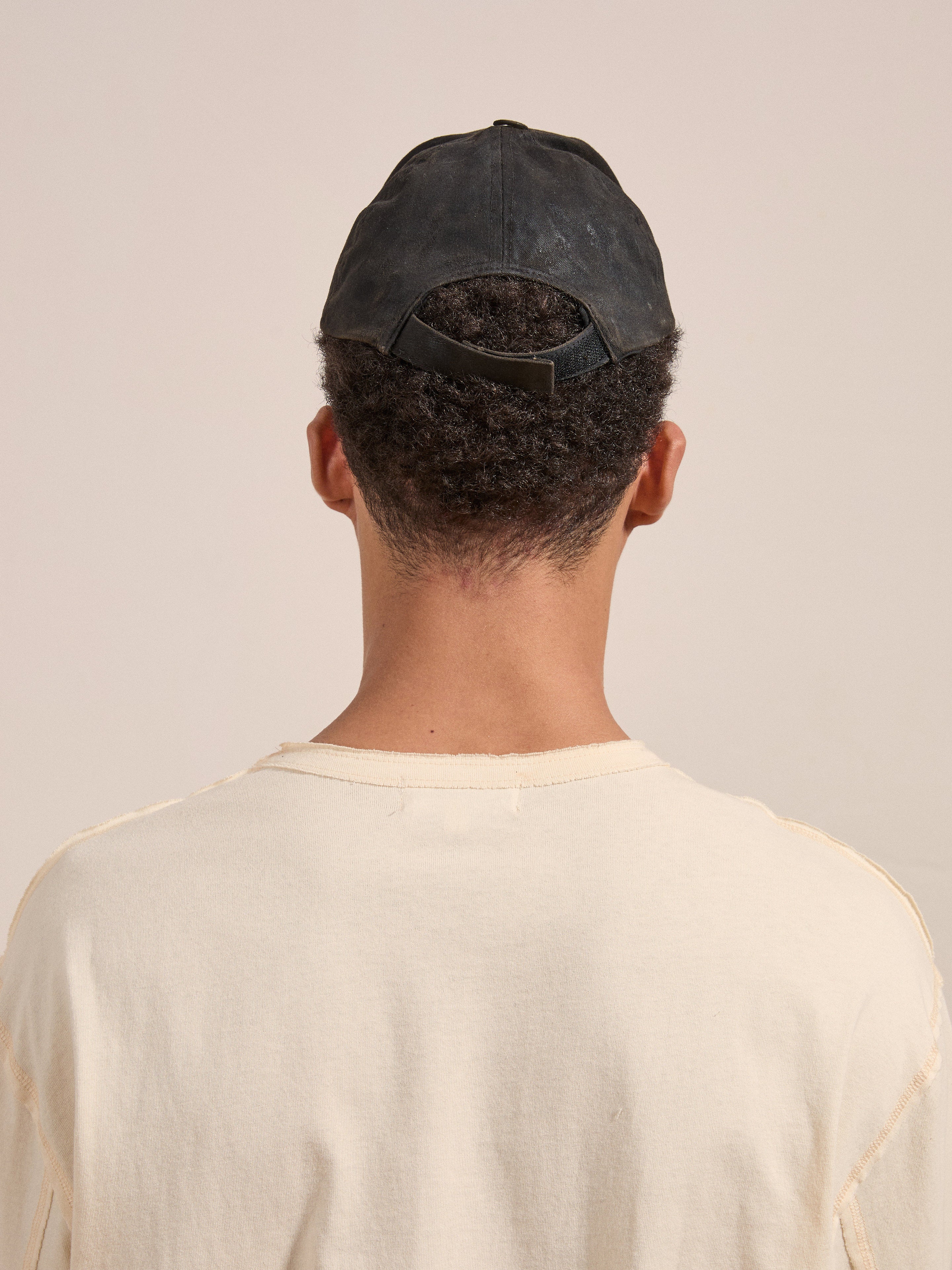 Back view of a person wearing the FOUND Waxed Charcoal Studded Cap and a beige shirt.