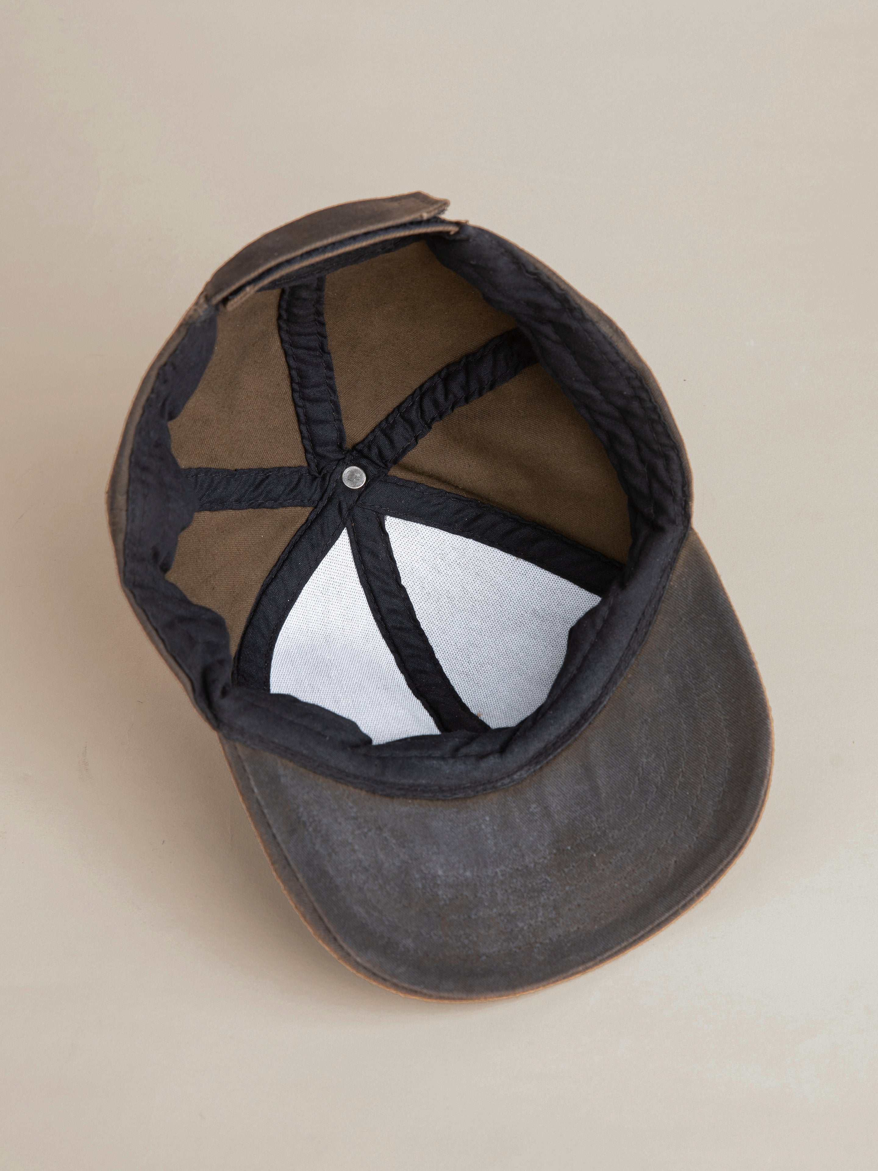 This image showcases the interior of the FOUND Waxed Charcoal Studded Cap, highlighting a visible sweatband and adjustable strap.