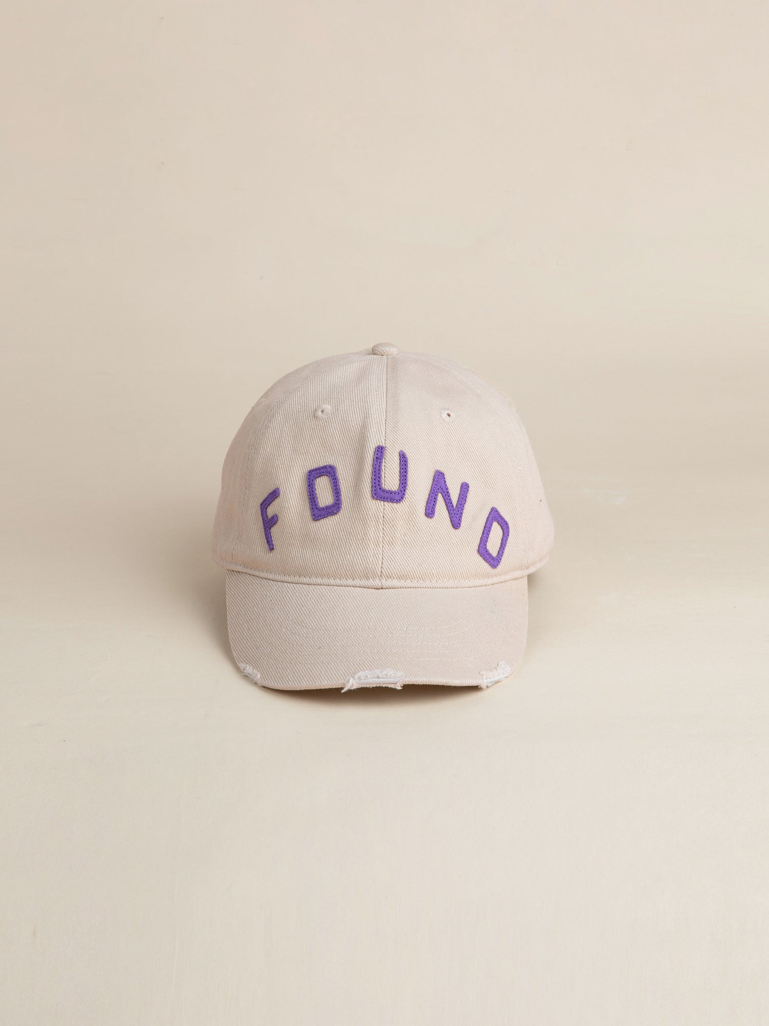 An ivory felt patch cap featuring a vintage washed fabric 6-panel design with a curved brim and the brand name 