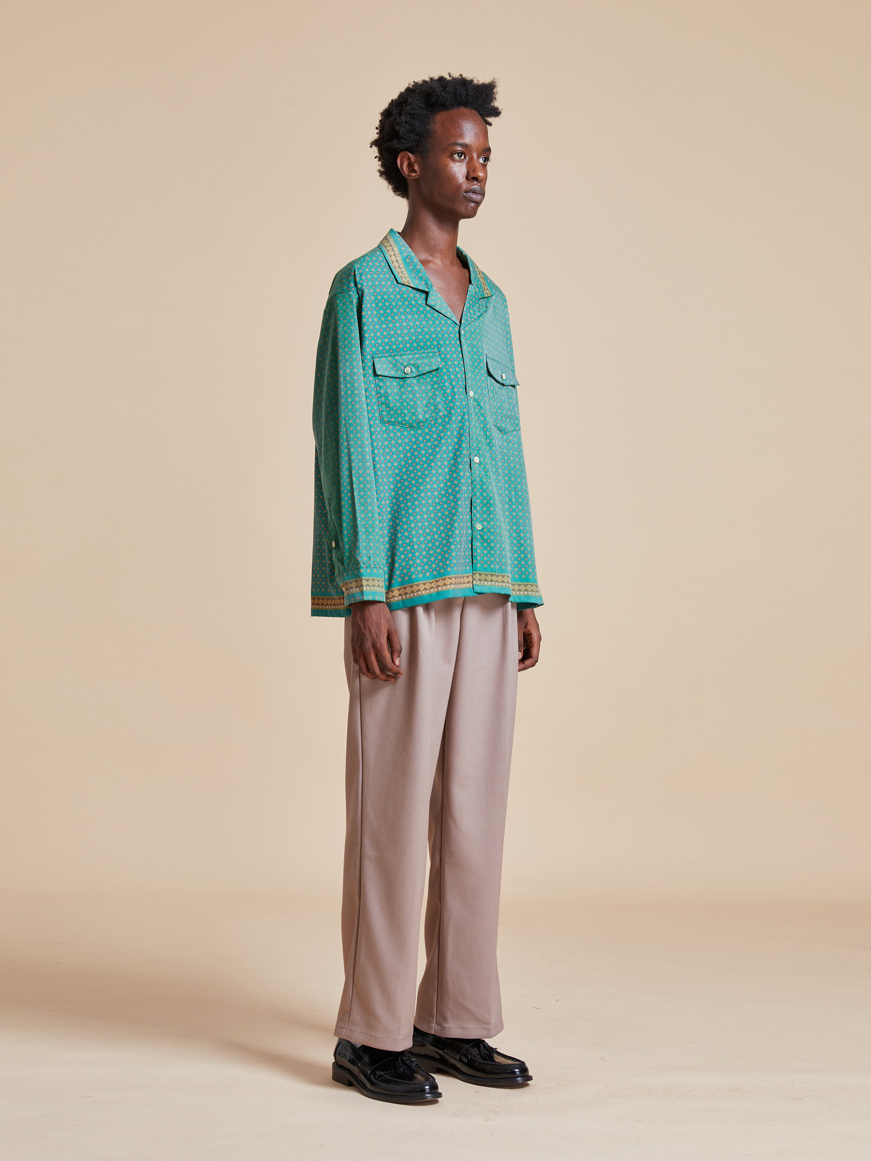 A man wearing a green Found Arbor Long Sleeve Camp Shirt and tan pants.