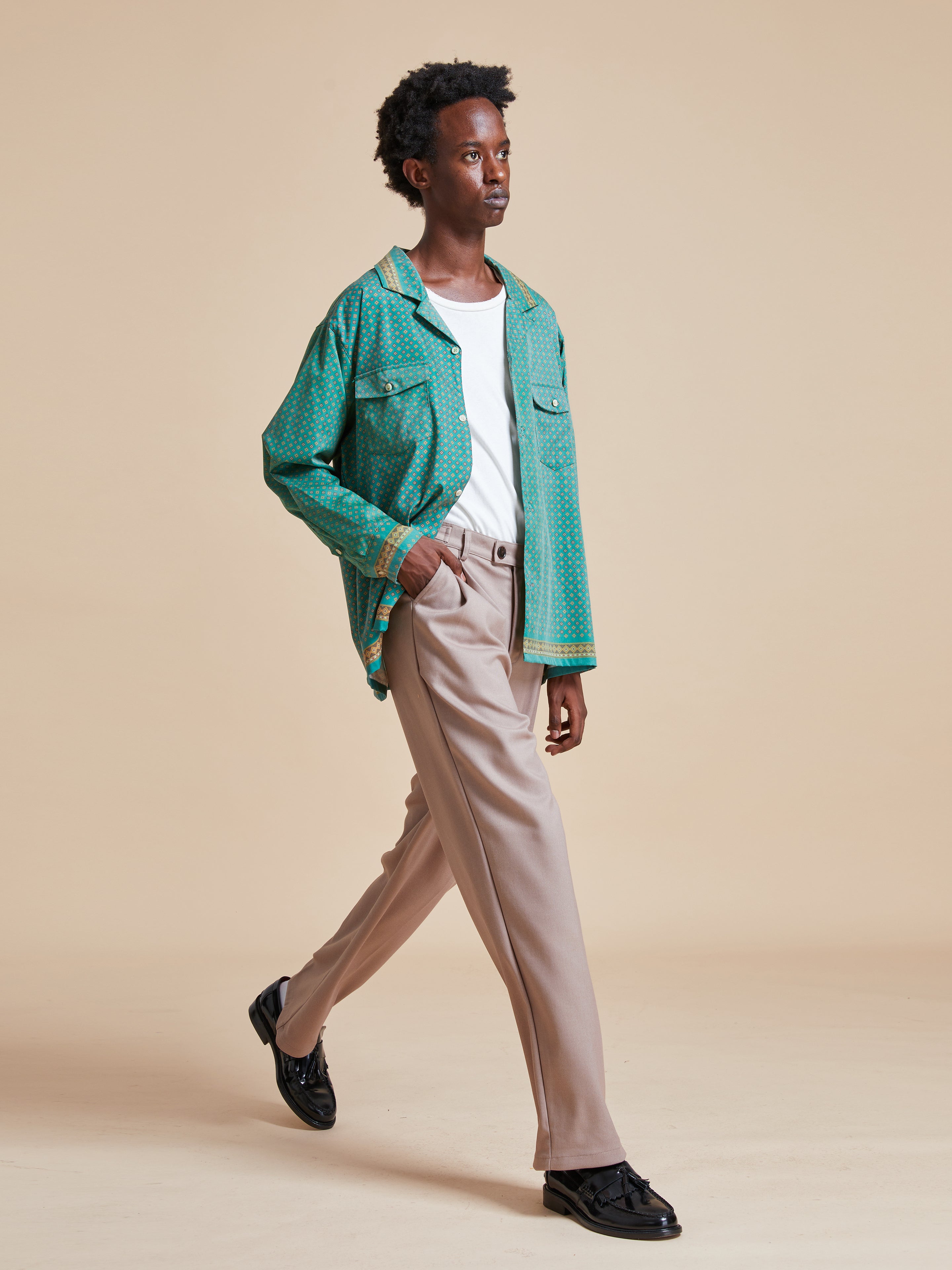 A man in a green Found Arbor Long Sleeve Camp Shirt walking on a beige background.