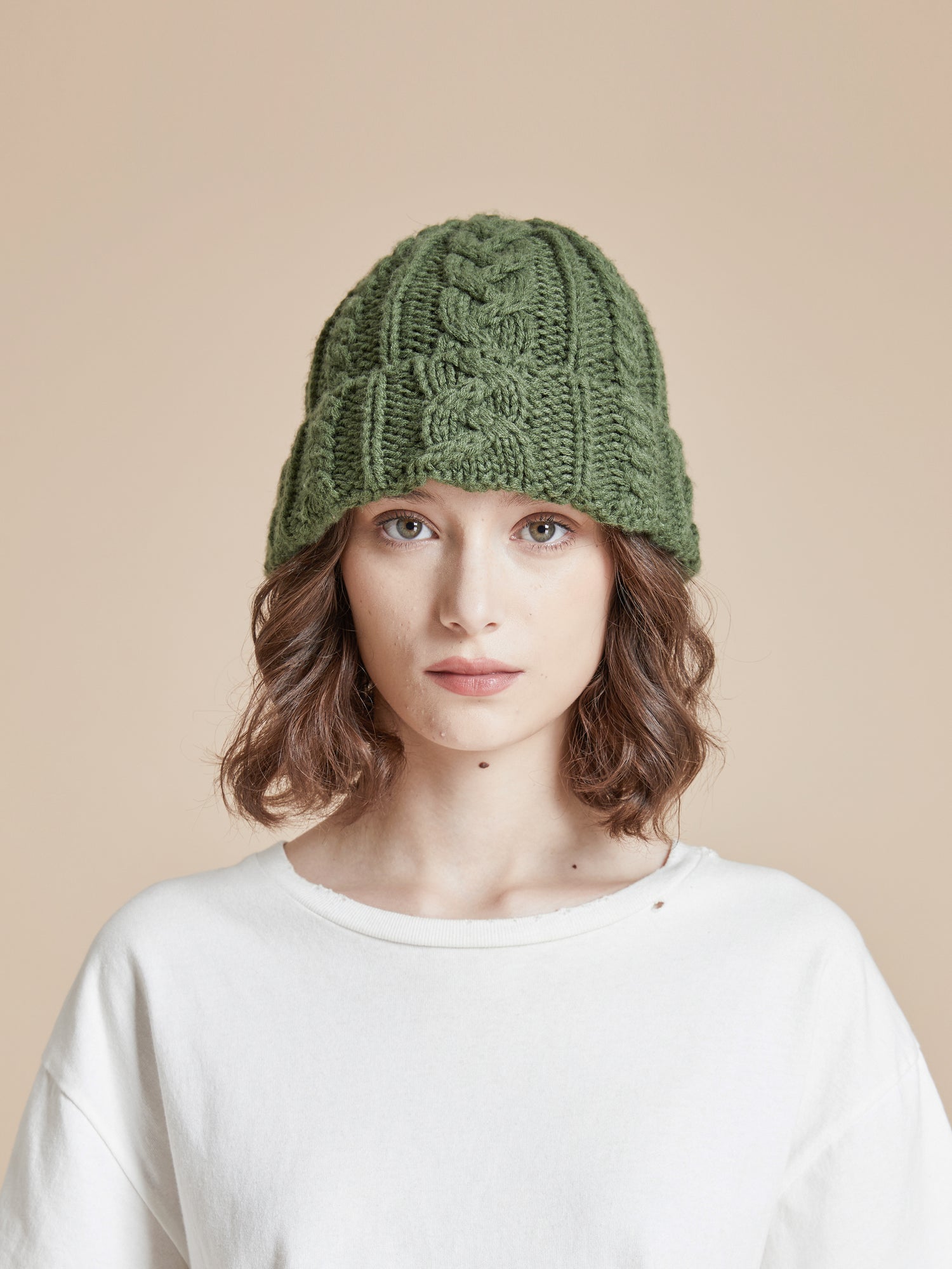 A woman wearing a Profound Forest Cable Knit Beanie hat.