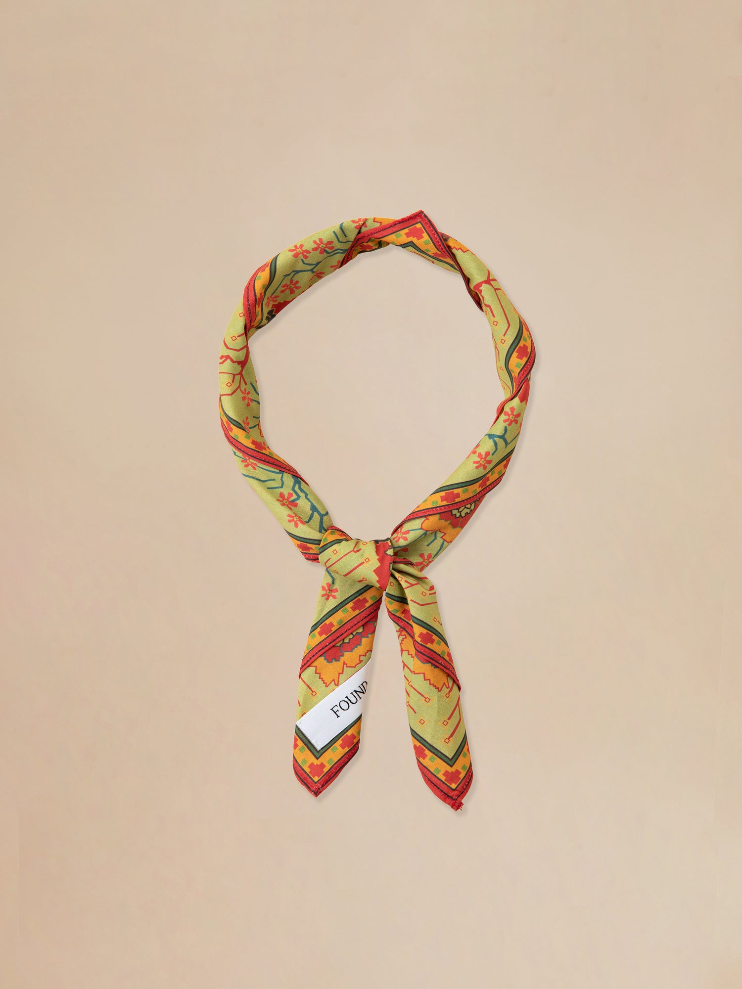 A yellow and red Botanical Mosaic Bandana with a white tag made by Found.