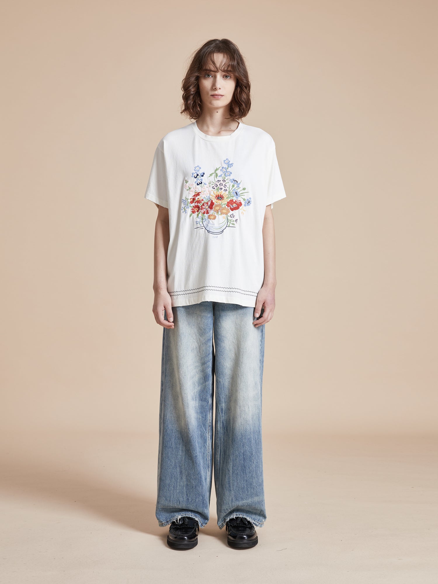 A woman wearing a Bouquet Flowers Tee by Found and blue jeans.