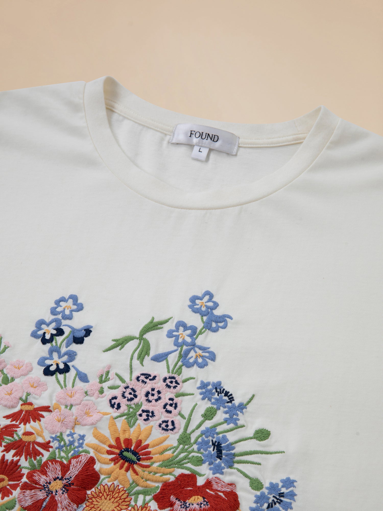 A white Bouquet Flowers Tee by Found with embroidered flowers on it.
