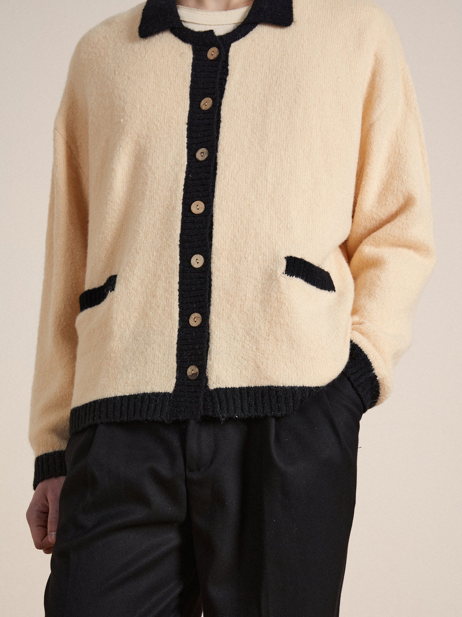 A man wearing a luxurious fuzzy textured fabric Found Sima Contrast Collar Knitted Cardigan with wooden buttons and pants.