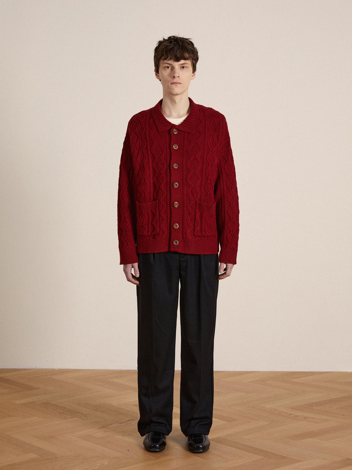 A person standing in a room wearing a Found Parsidan Cable Knit Cardigan.