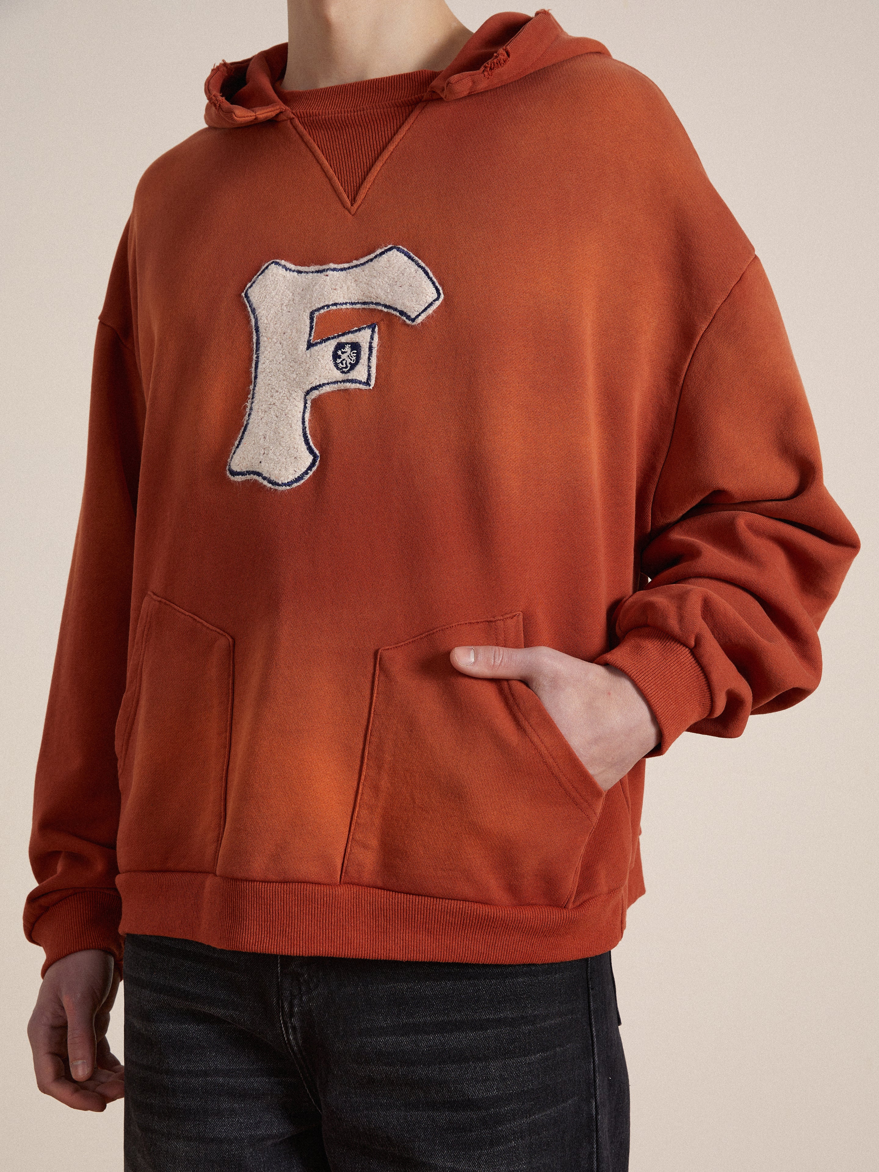 A man wearing a Found enzyme washed cotton hoodie with a Faded "F" on it.