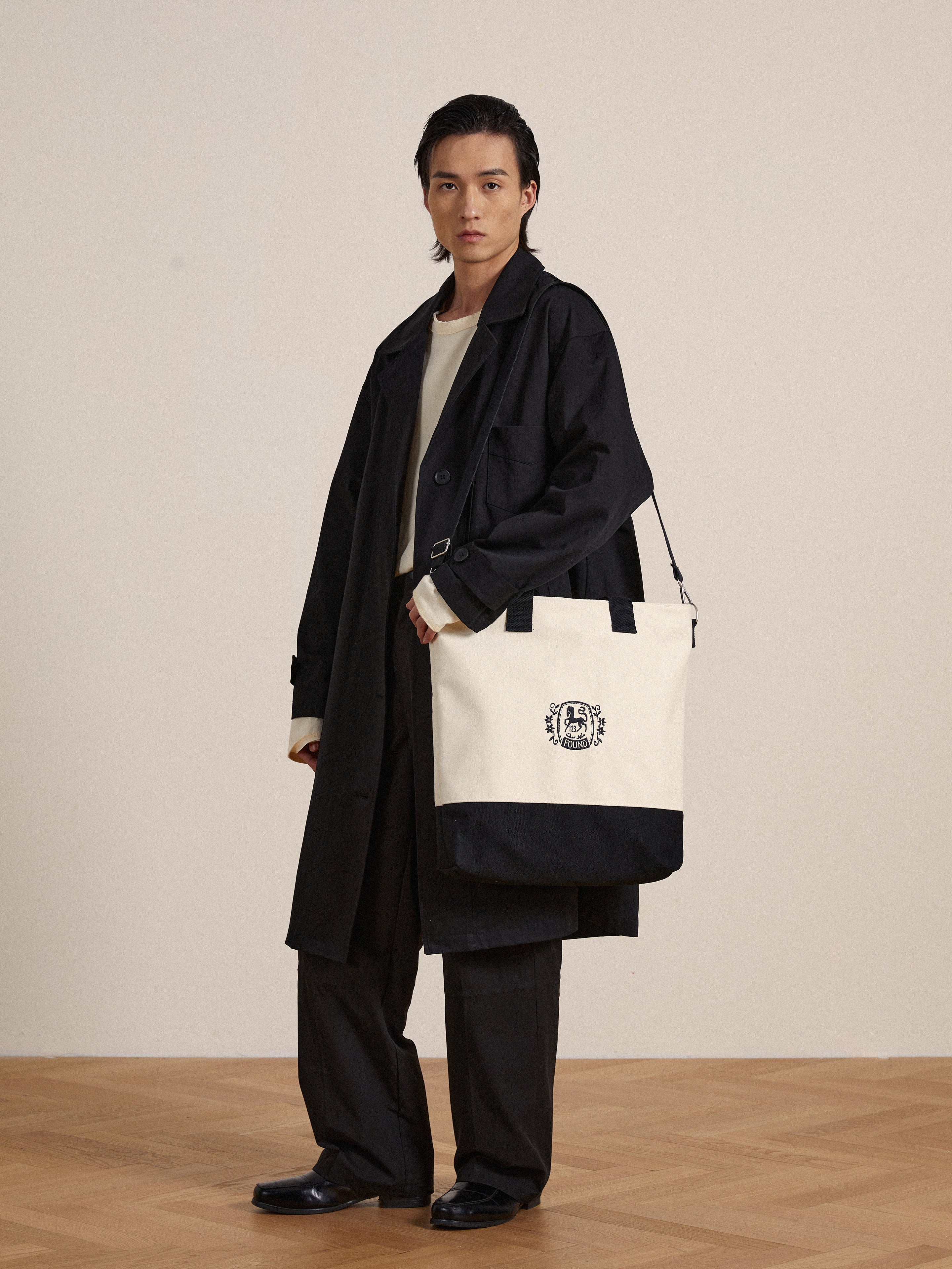 A man is holding a distinctive Profound Horse Logo Crest Canvas Bag made from premium cotton twill.