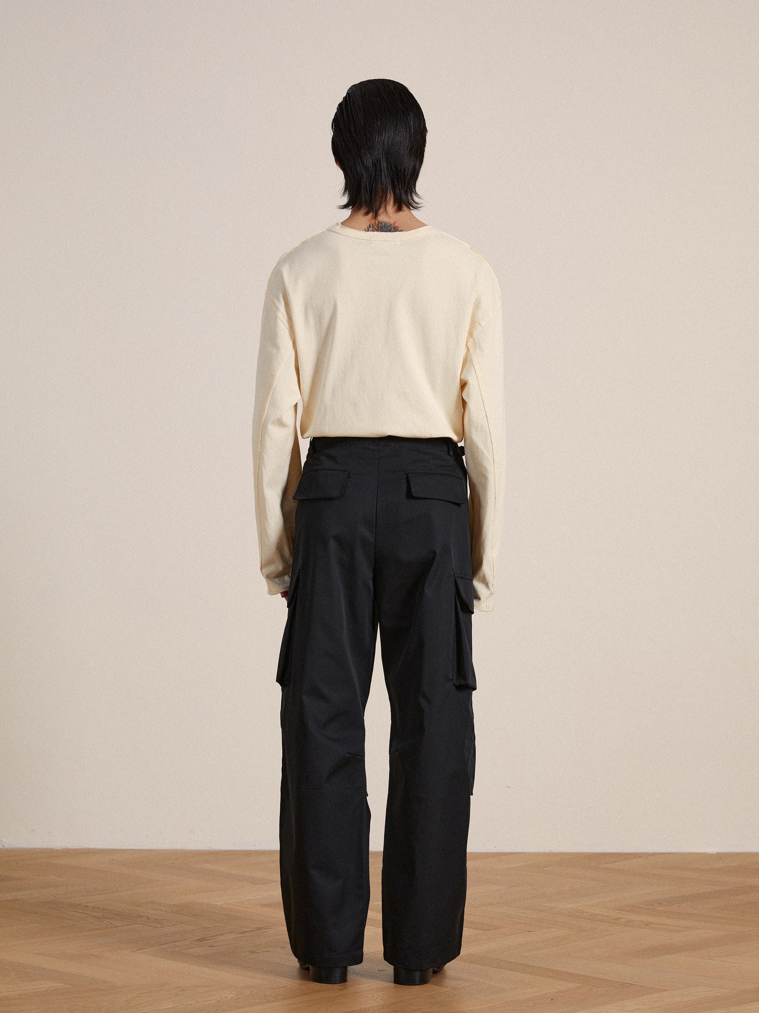 The back view of a man wearing black Found Elbas Cargo Pants with adjustable waist tabs.