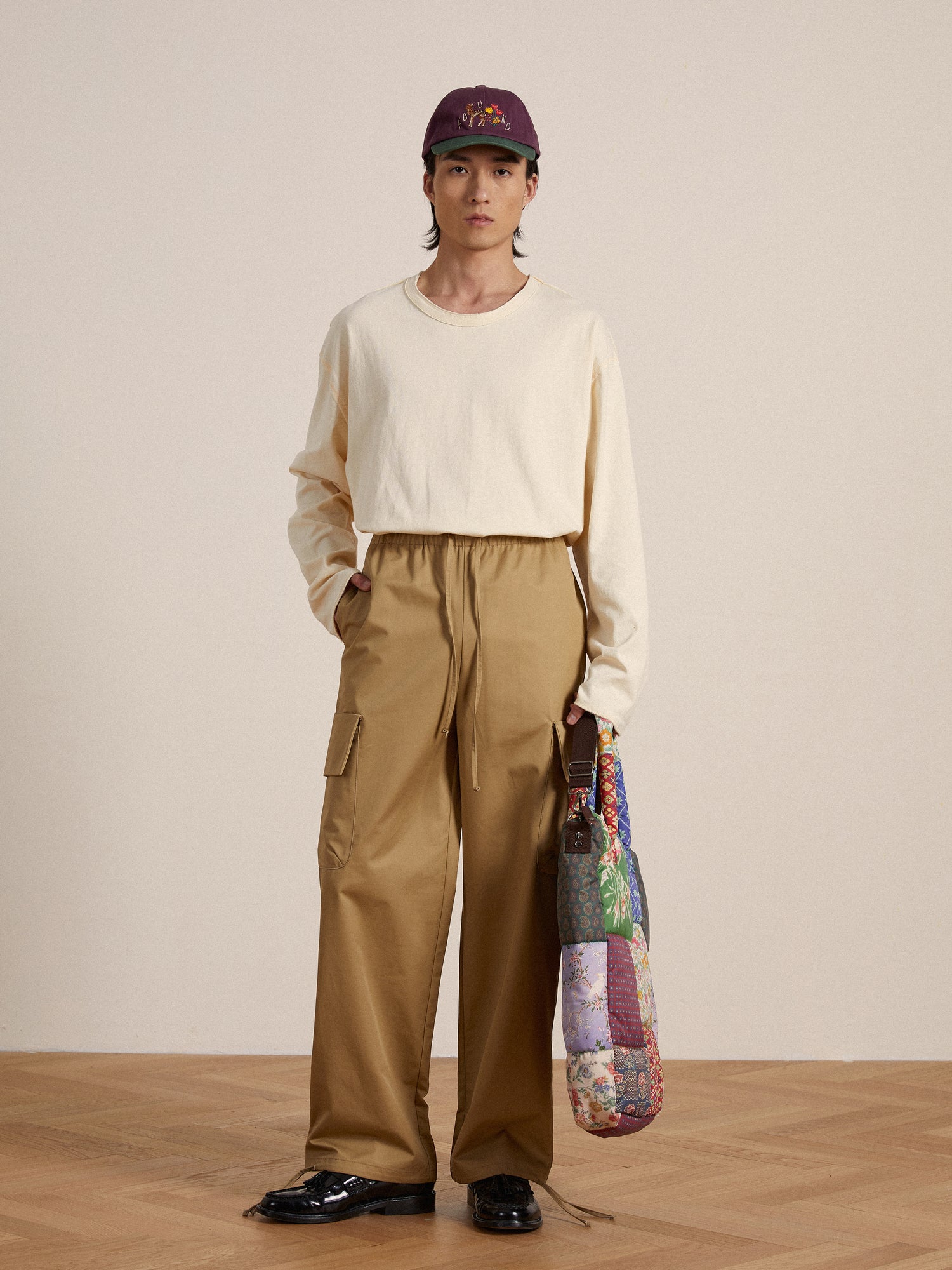 A man in a tan shirt and Found Twill Cargo Drawstring Pants made of lightweight fabric holding a bag.