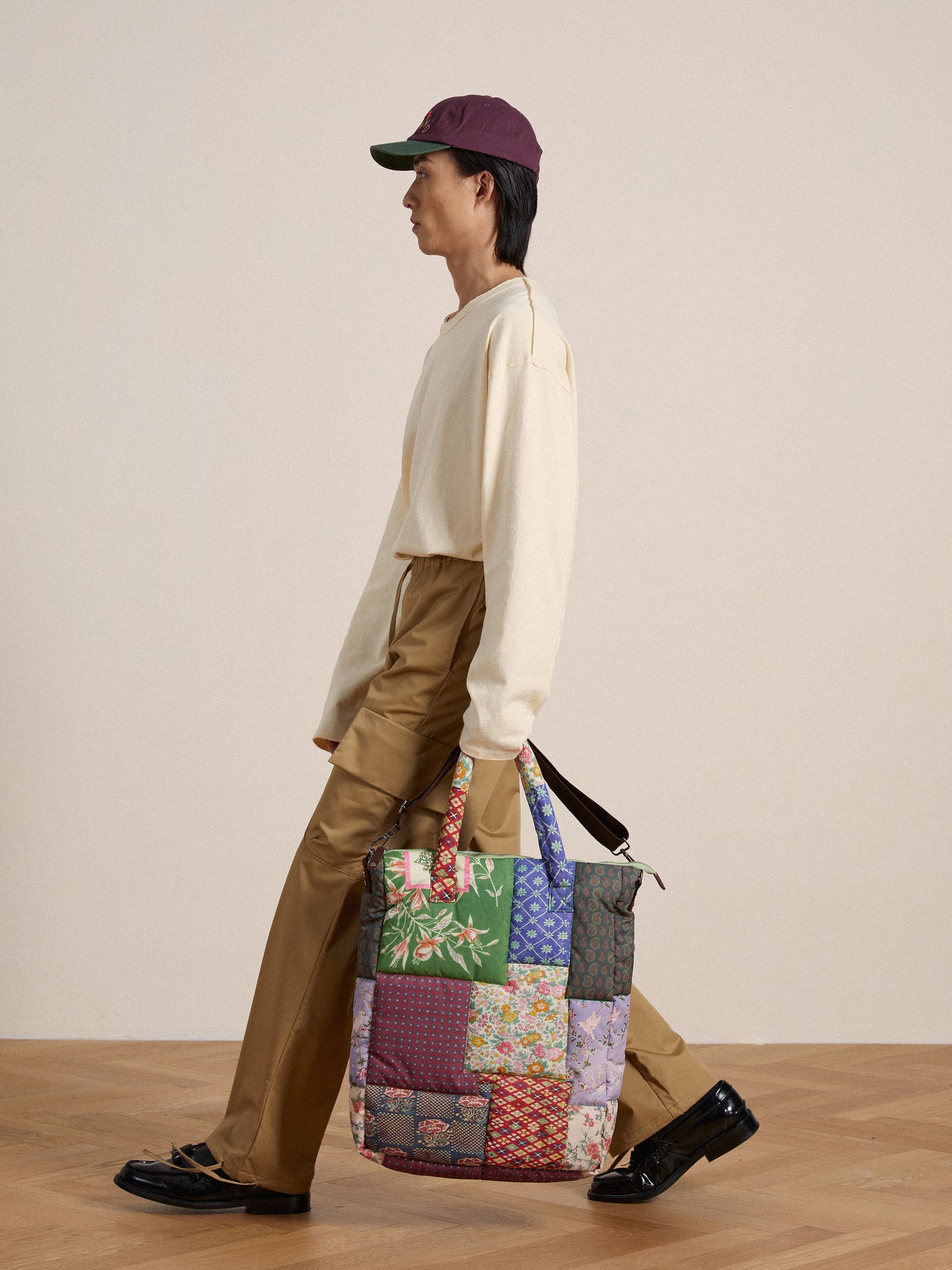 A man is carrying a colorful, lightweight fabric patchwork Found tote bag.