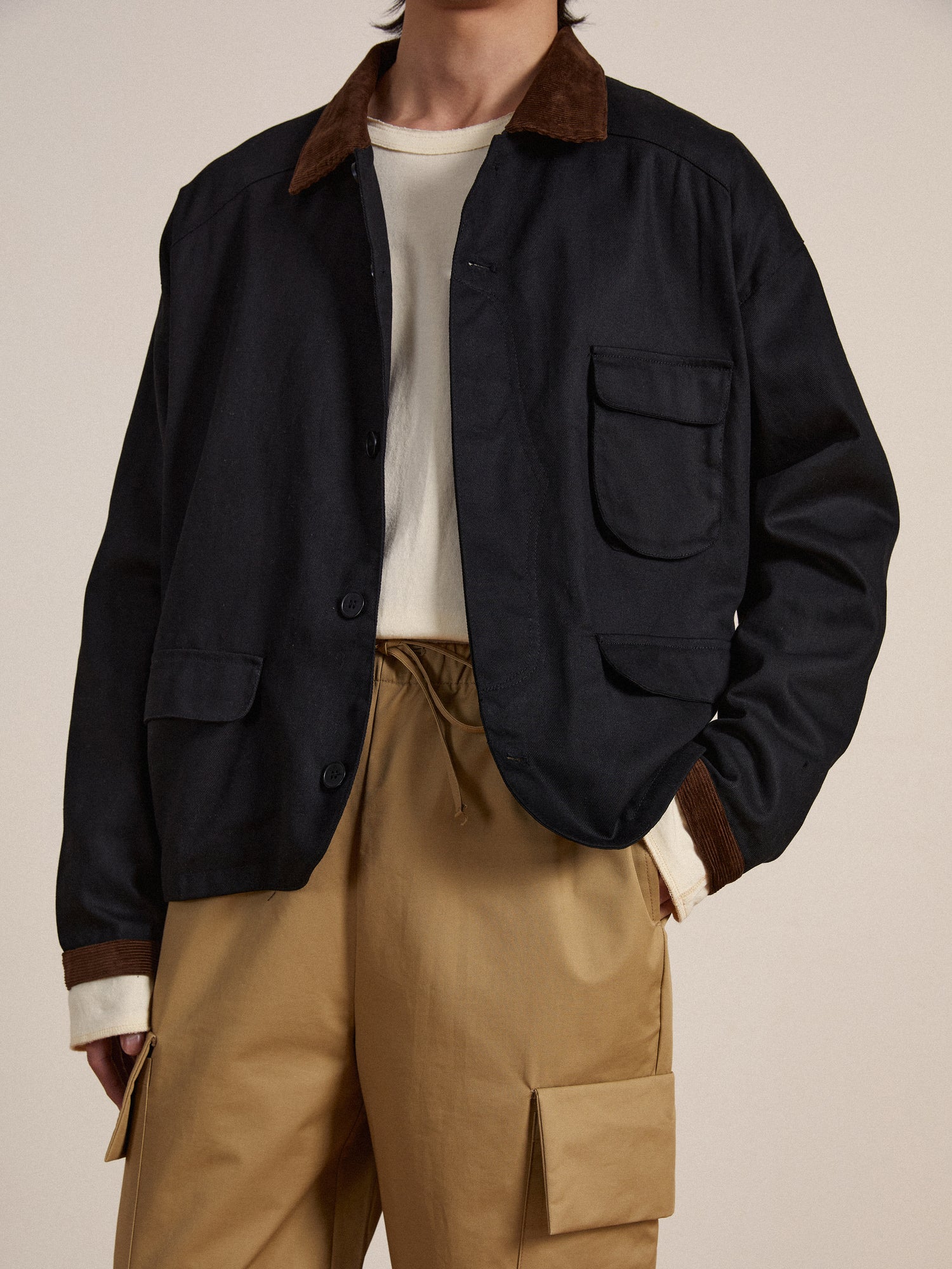 The model is wearing a Found Lar Waxed Cotton Box Coat and tan cargo pants.