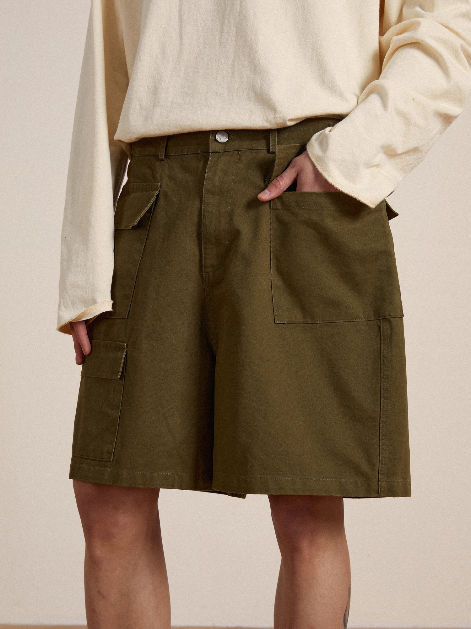 A man wearing Found twill cargo shorts with adjustable waist tabs and a white t-shirt.