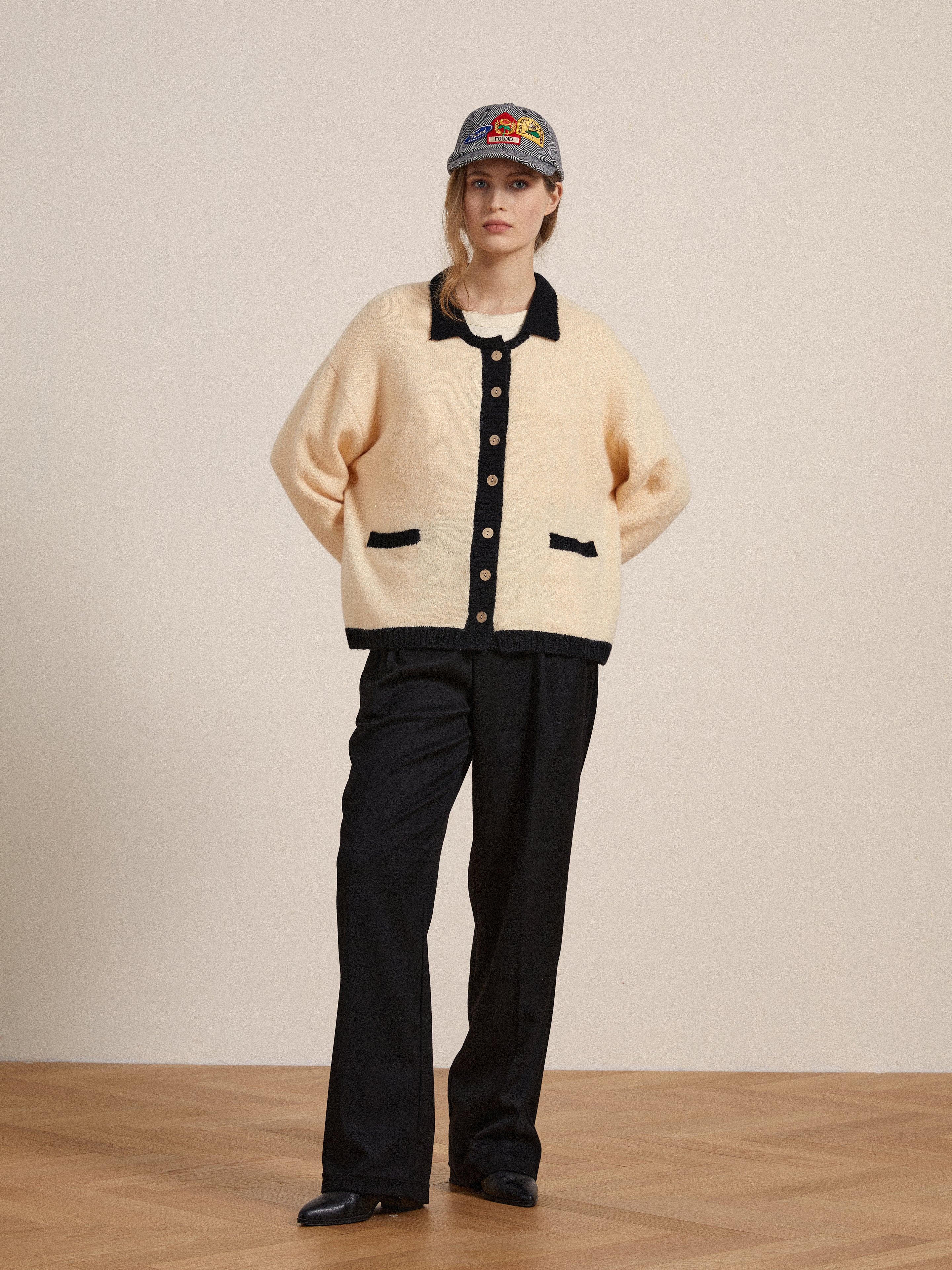 A woman wearing a Found Sima Contrast Collar Knitted Cardigan with wooden buttons and black pants.