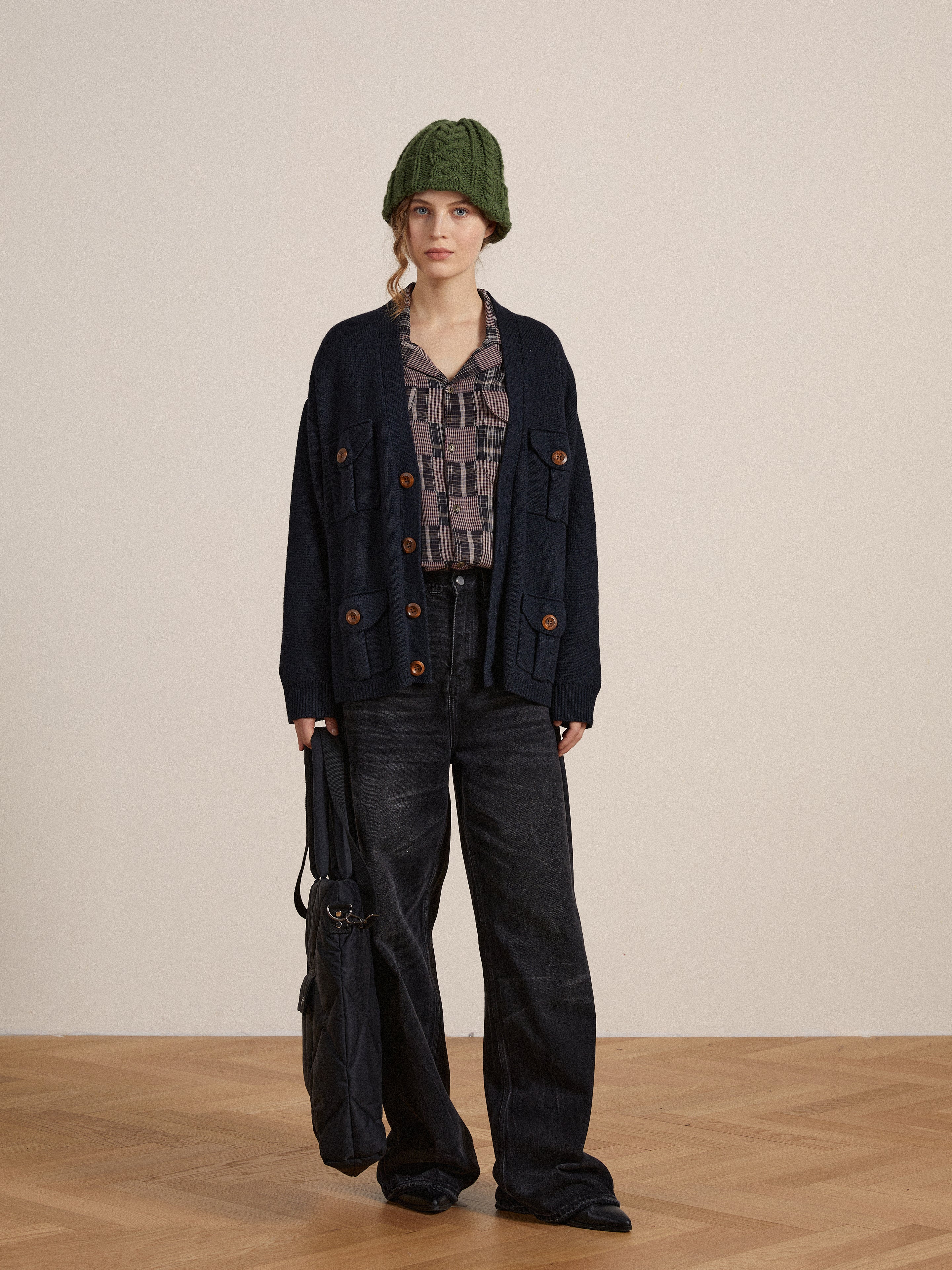 A woman is standing on a wooden floor wearing a timeless silhouette hat and Lacy Baggy Jeans by Found.