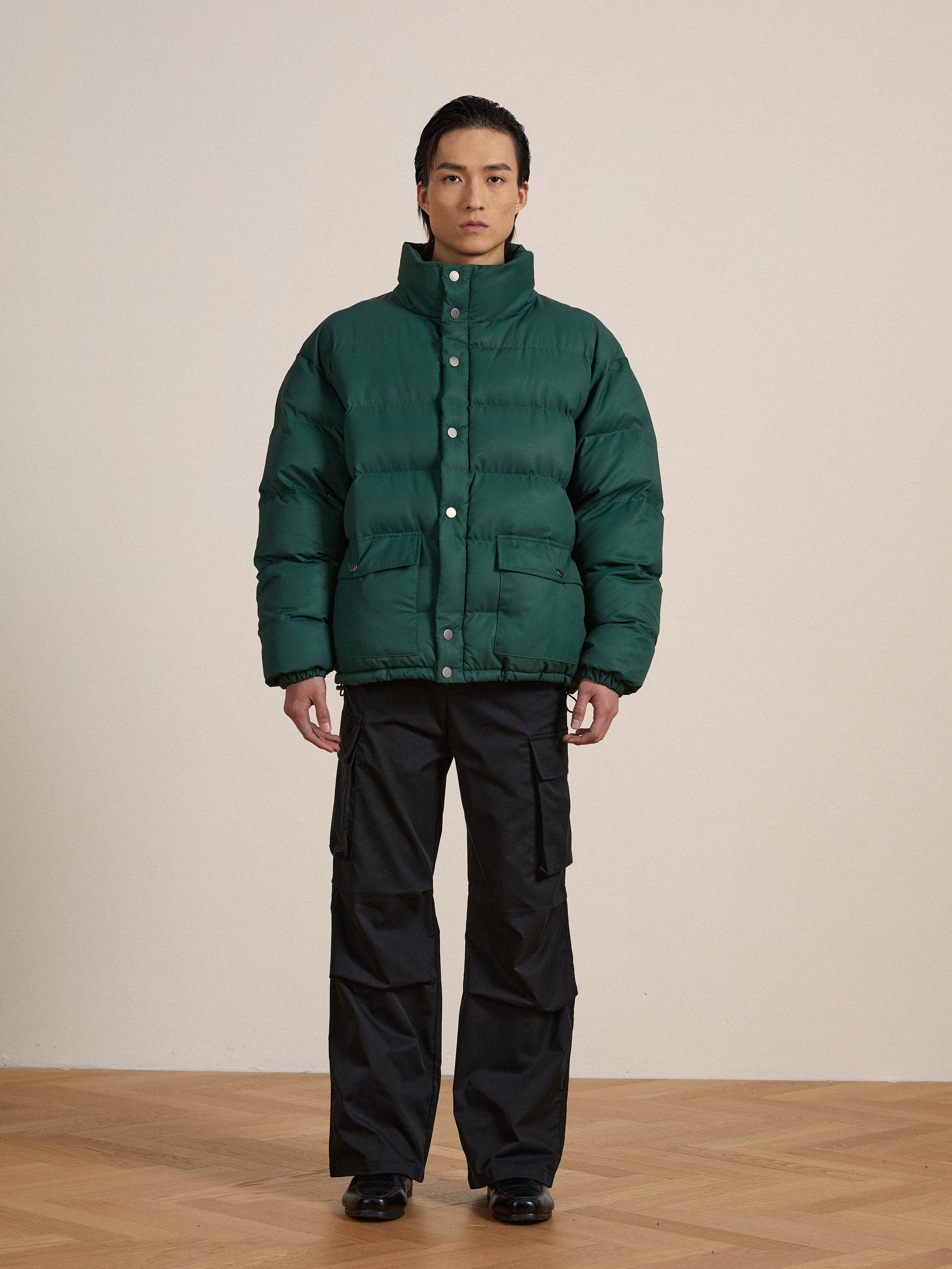 A man in a Found Laurel Pine Puffer Jacket standing on a wooden floor.